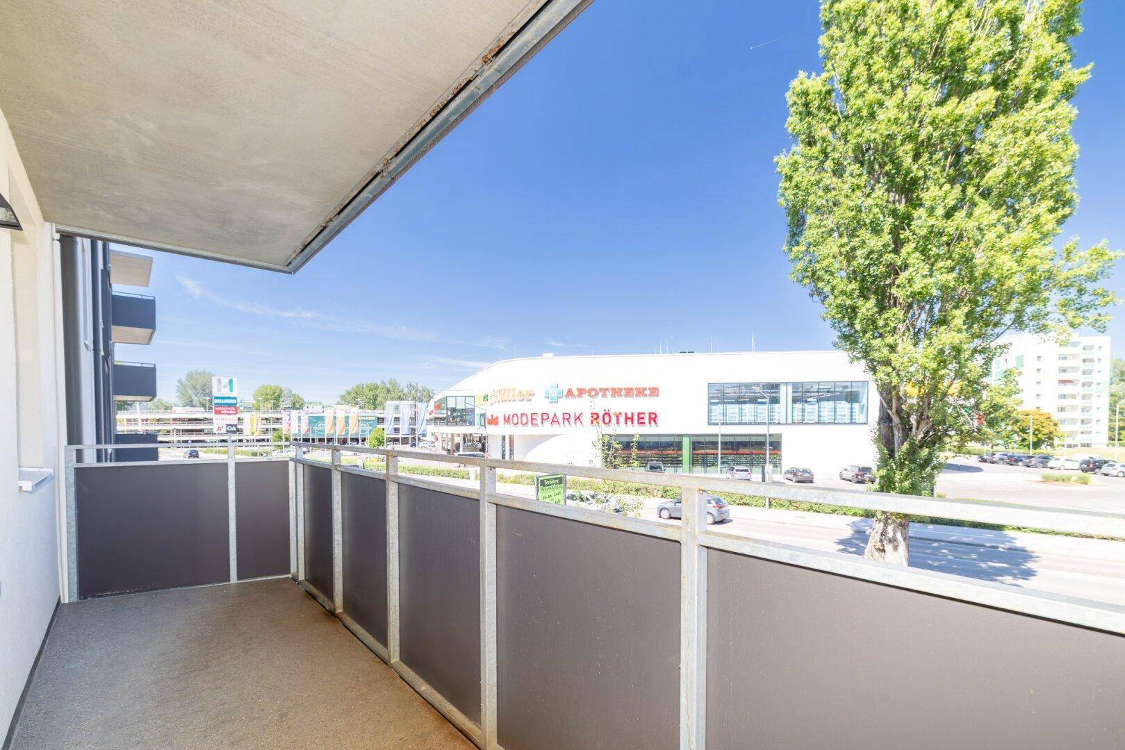 Balkon mit Blick auf eine belebte Straße und ein nahegelegenes Einkaufszentrum.
