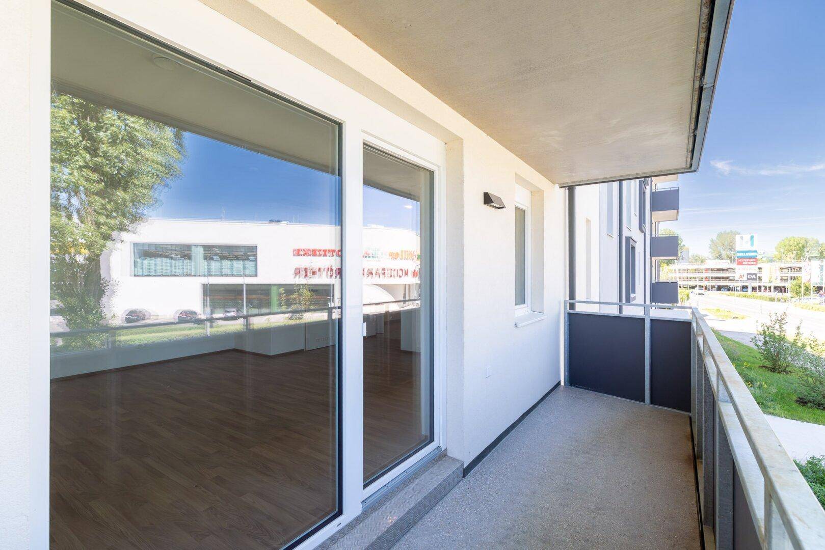 Heller Balkon mit Blick auf die Umgebung und den Zugang zum Innenbereich der Wohnung.