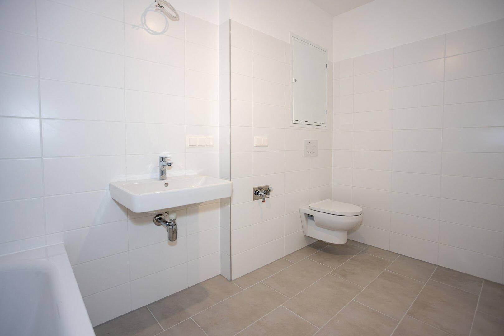 Helles Badezimmer mit modernen Armaturen, wandhängendem WC und Waschbecken.