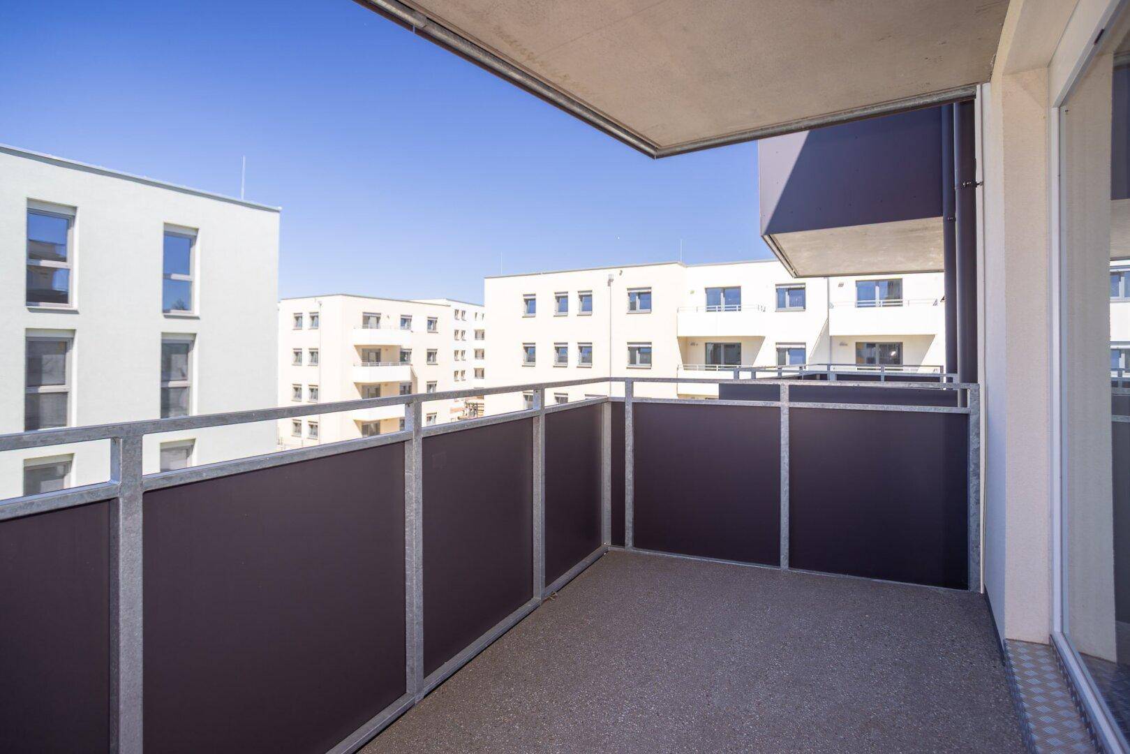 Moderner Balkon mit Blick auf die umliegenden Wohngebäude unter blauem Himmel.