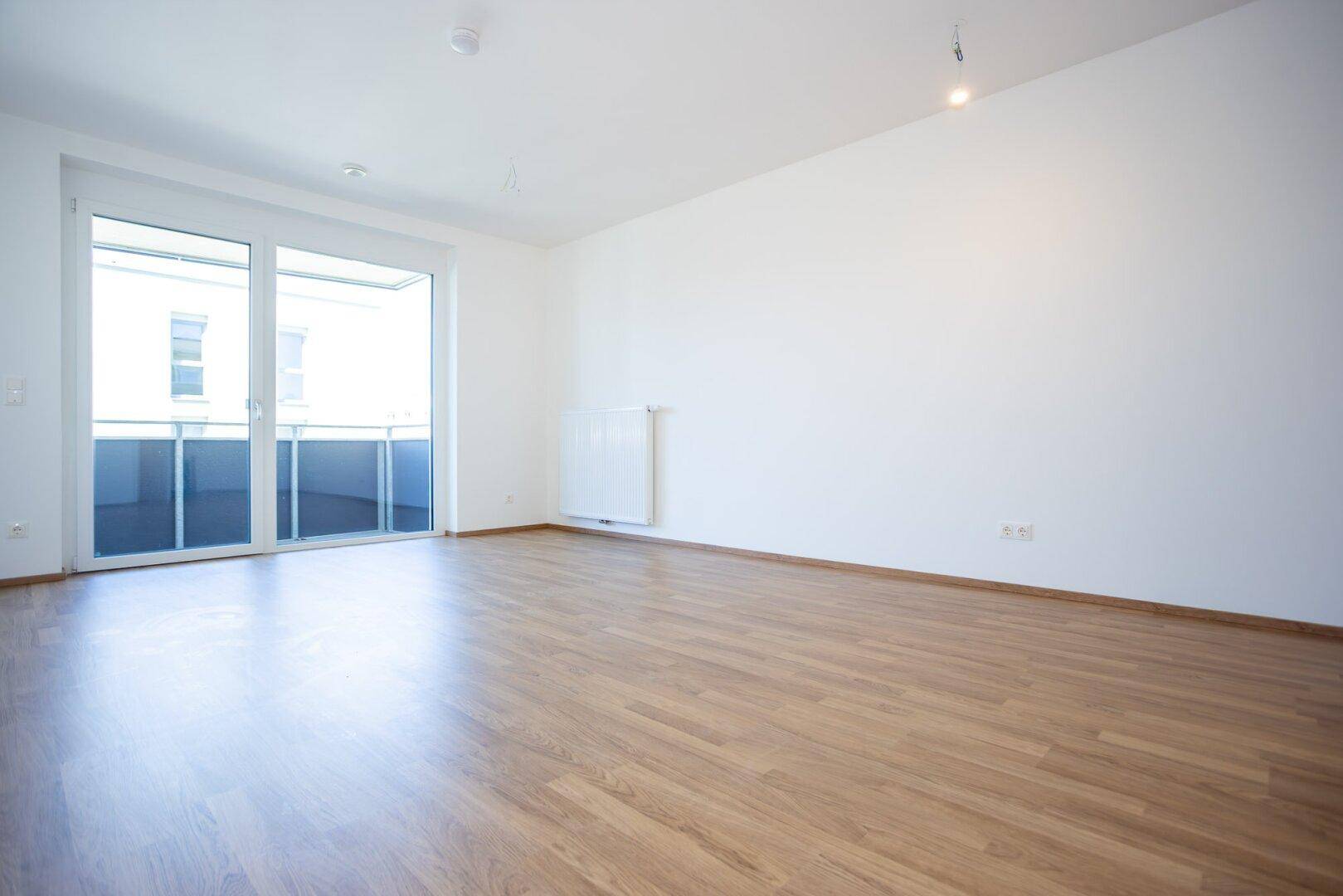 Geräumiges, helles Zimmer mit Laminatboden und Heizkörper, bereit für die individuelle Gestaltung.