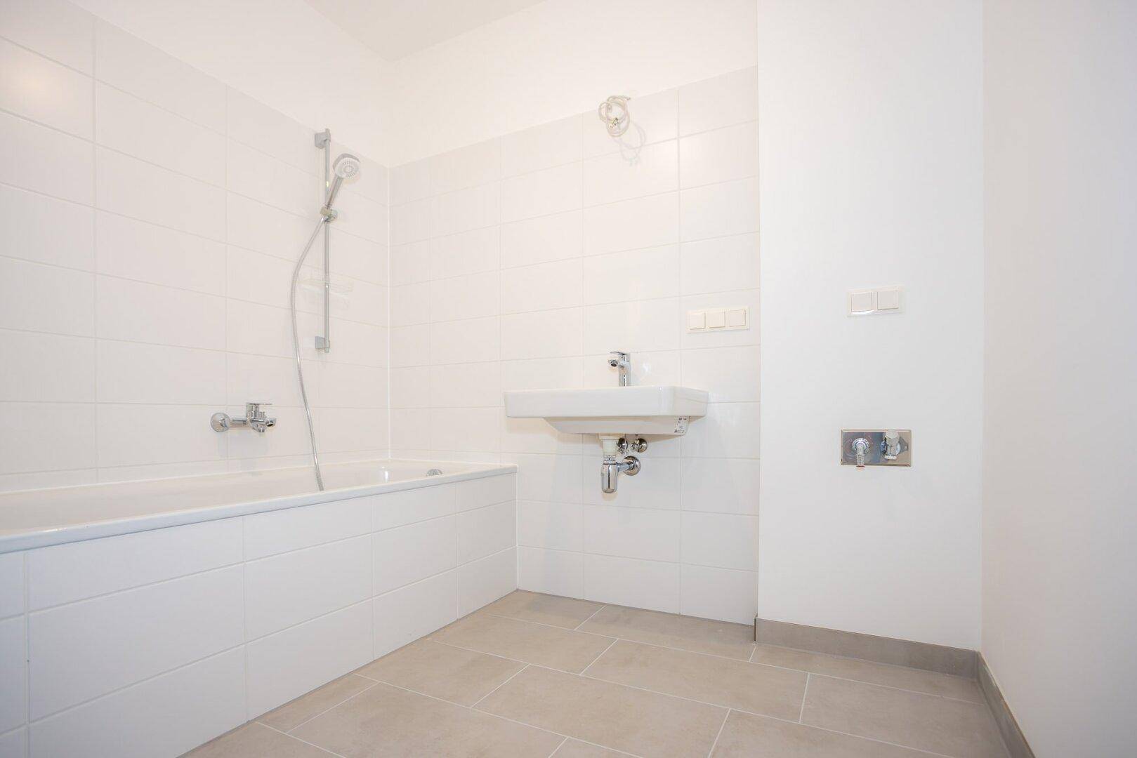 Modernes Badezimmer mit weißen Fliesen, Badewanne und einem einzelnen Waschbecken.