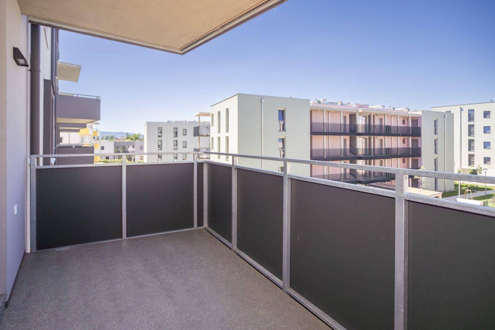 Heller Balkon mit schlichtem Design und Aussicht auf die moderne Wohnanlage.