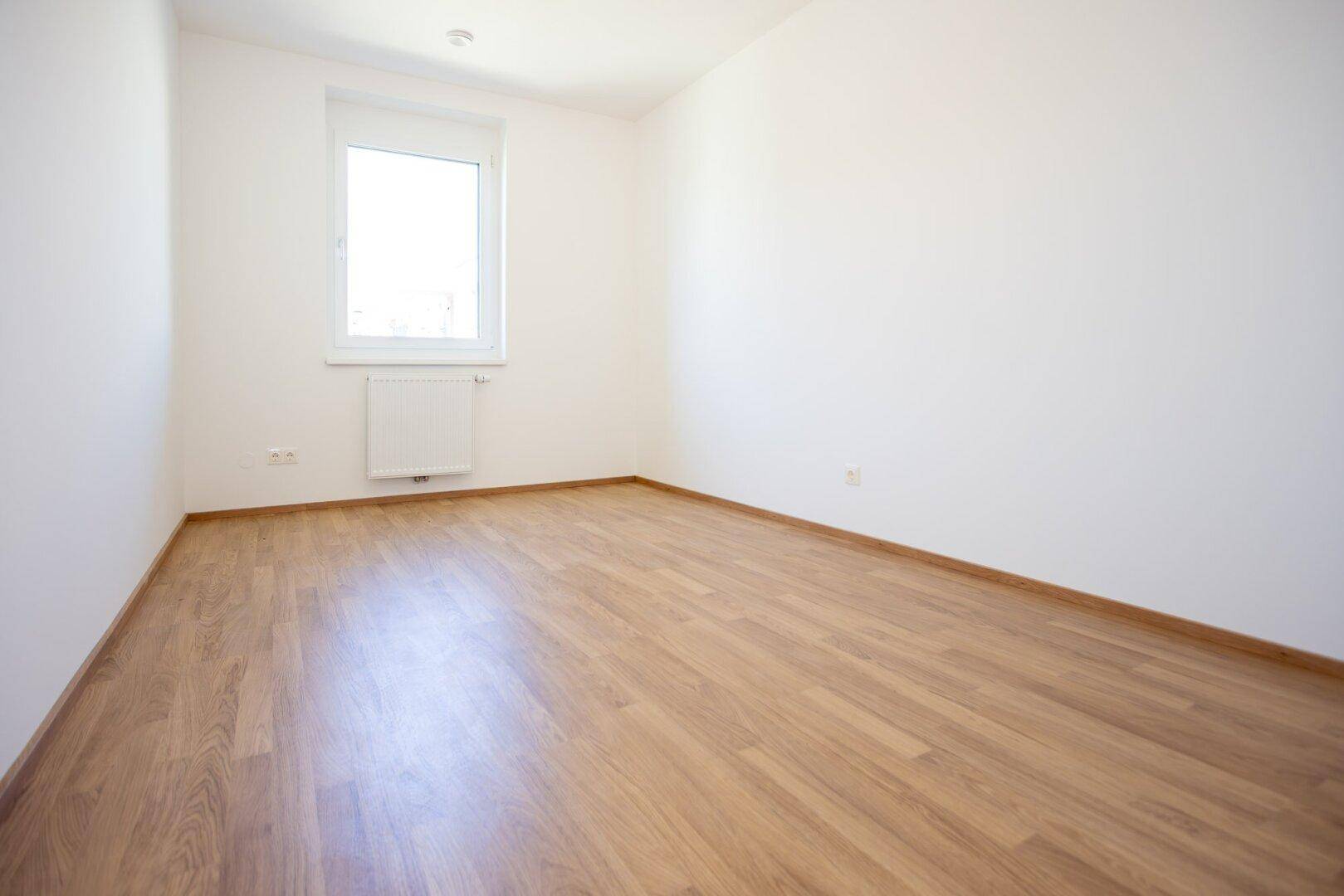 Geräumiges, helles Zimmer mit Laminatboden und Fenster, ideal als Schlaf- oder Arbeitszimmer.