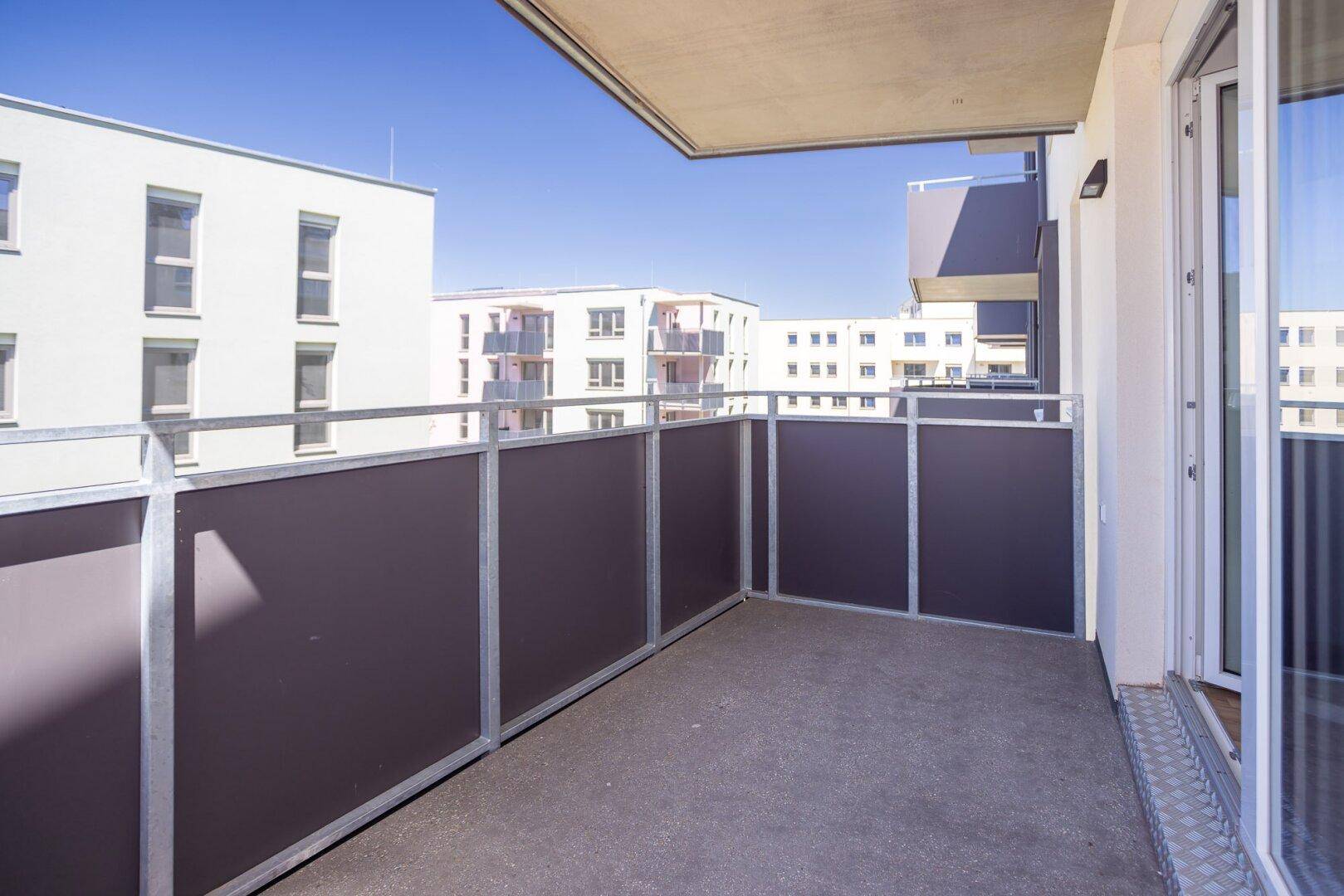 Sonniger Balkon mit Blick auf moderne Wohngebäude in einer städtischen Umgebung.