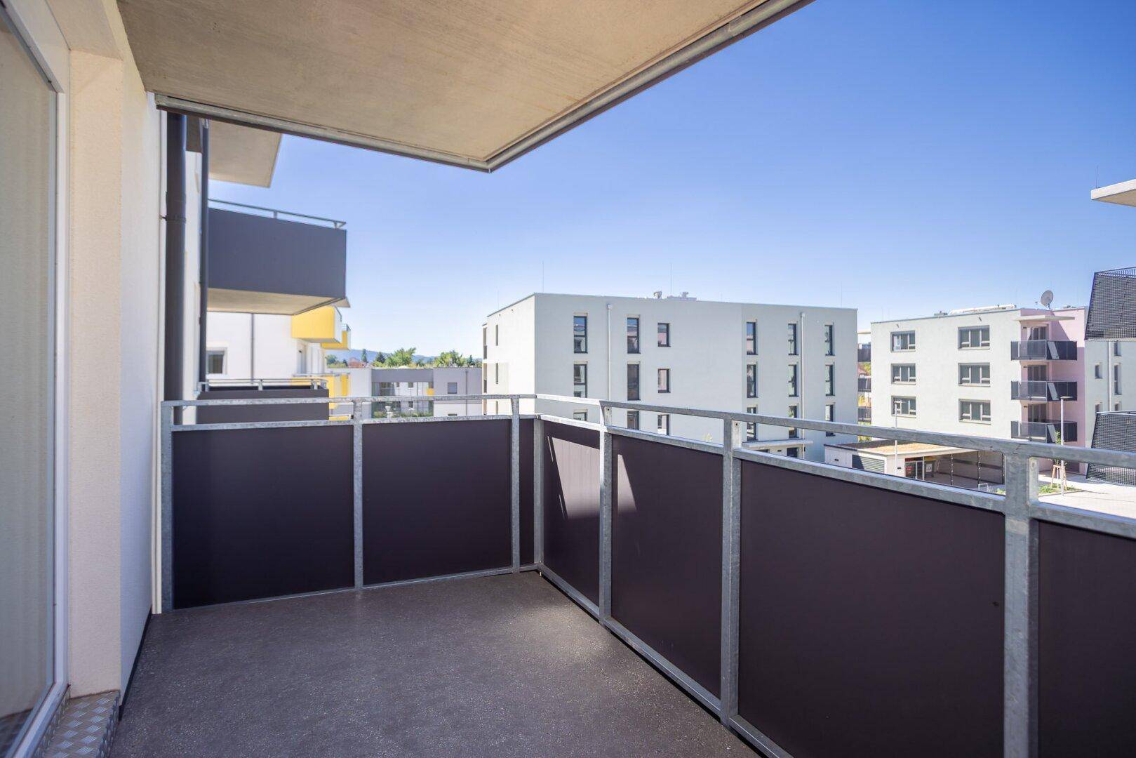 Heller Balkon mit Metallgeländer und weitem Blick auf die umliegenden Neubauten.