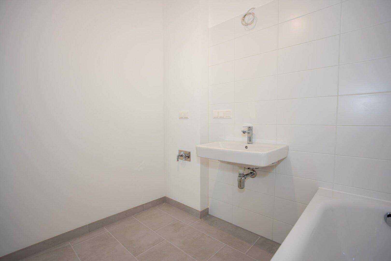 Helles Badezimmer mit modernem Waschbecken und weißen Wandfliesen.