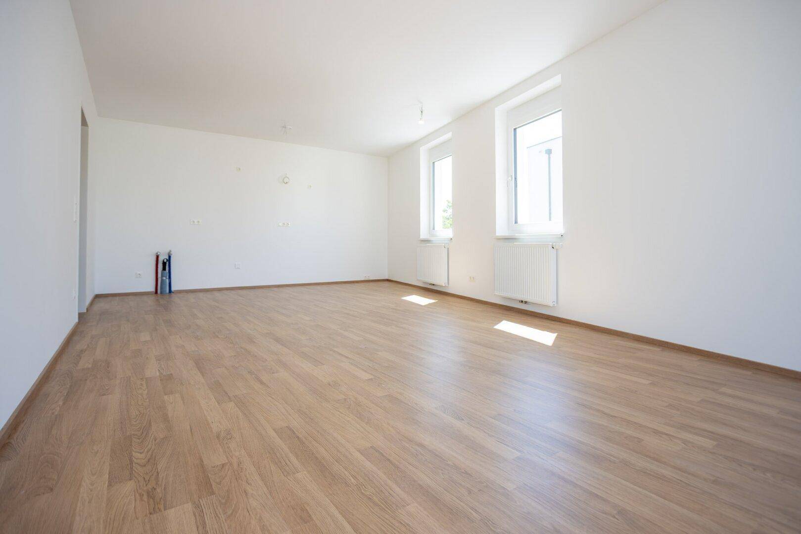 Heller und geräumiger Raum mit zwei Fenstern und neuem Laminatboden.