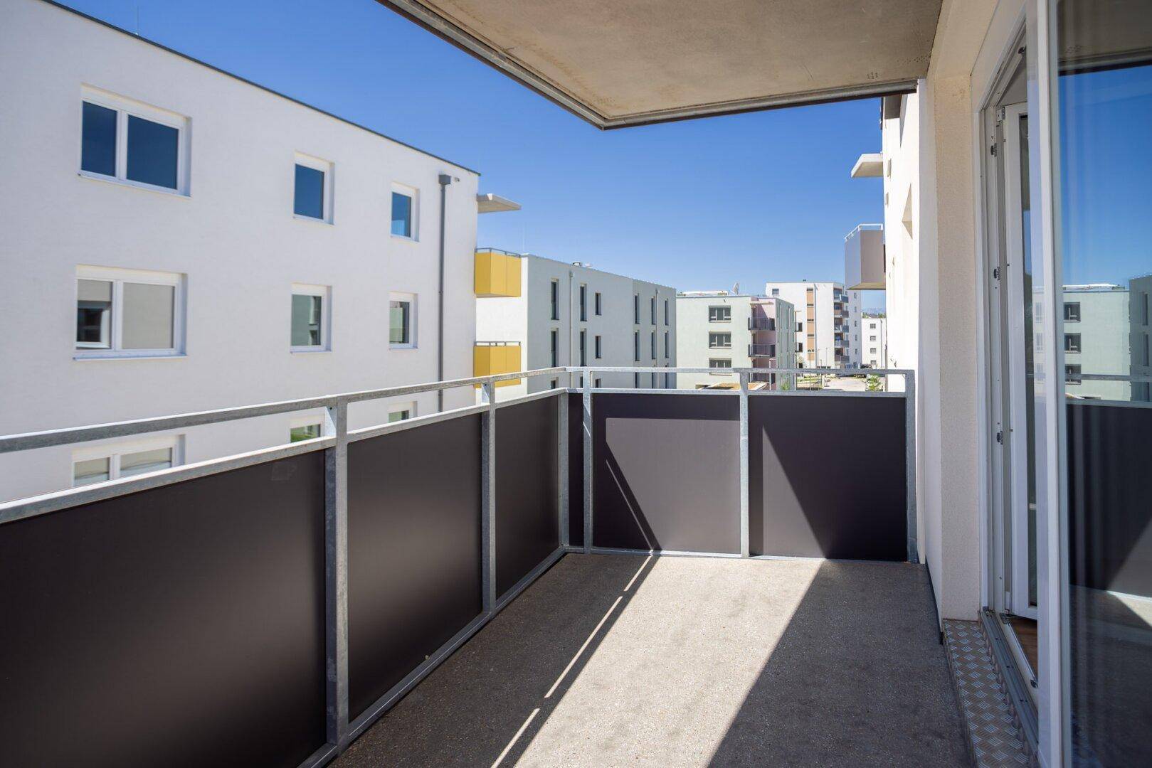 Geräumiger Balkon mit Blick auf die moderne Architektur der Wohnanlage.