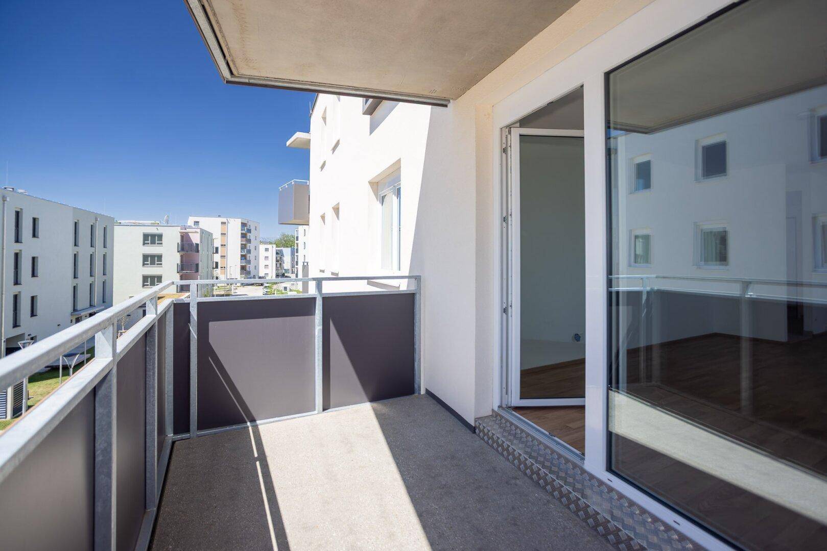 Moderner Balkon mit Metallgeländer und Blick auf umliegende Neubauten.
