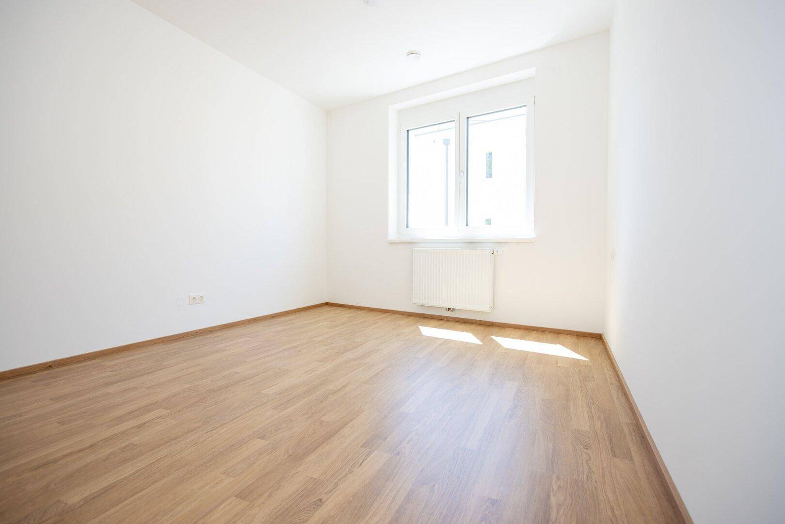 Leeres Schlafzimmer mit Parkettboden und weiß gestrichenen Wänden, bereit zum Einzug.