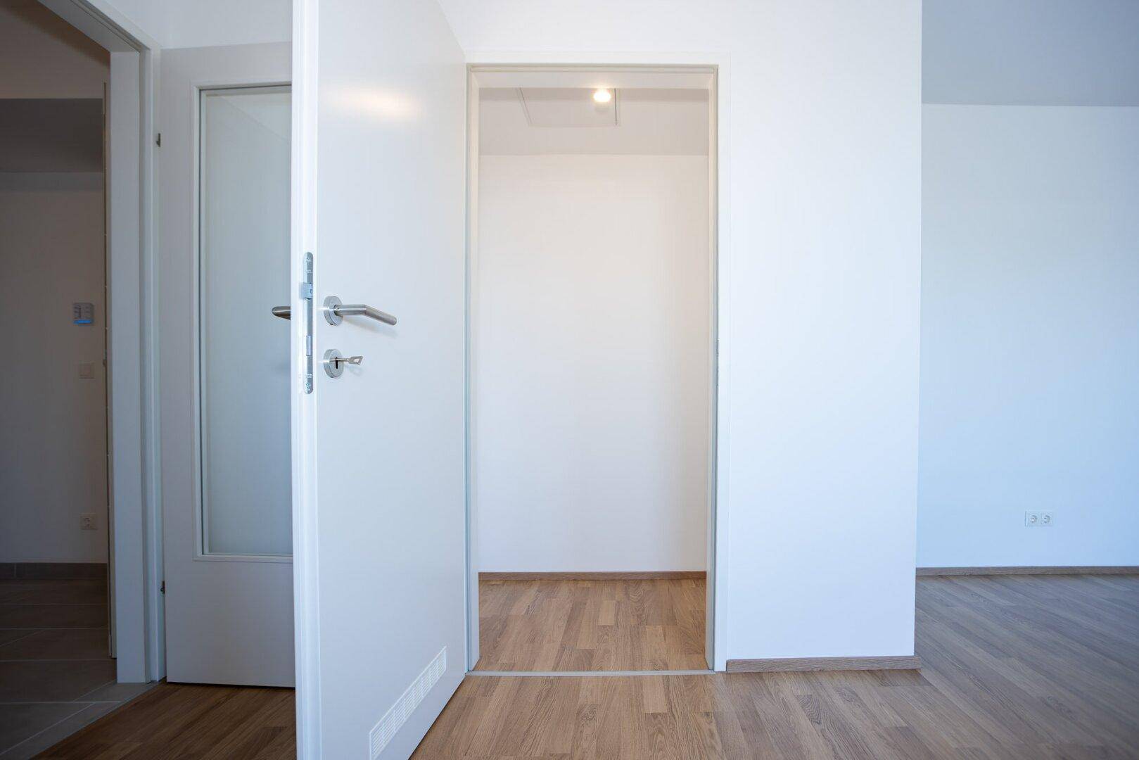 Heller Flurbereich mit Laminatboden und weißen Türen, der zu weiteren Räumen führt.