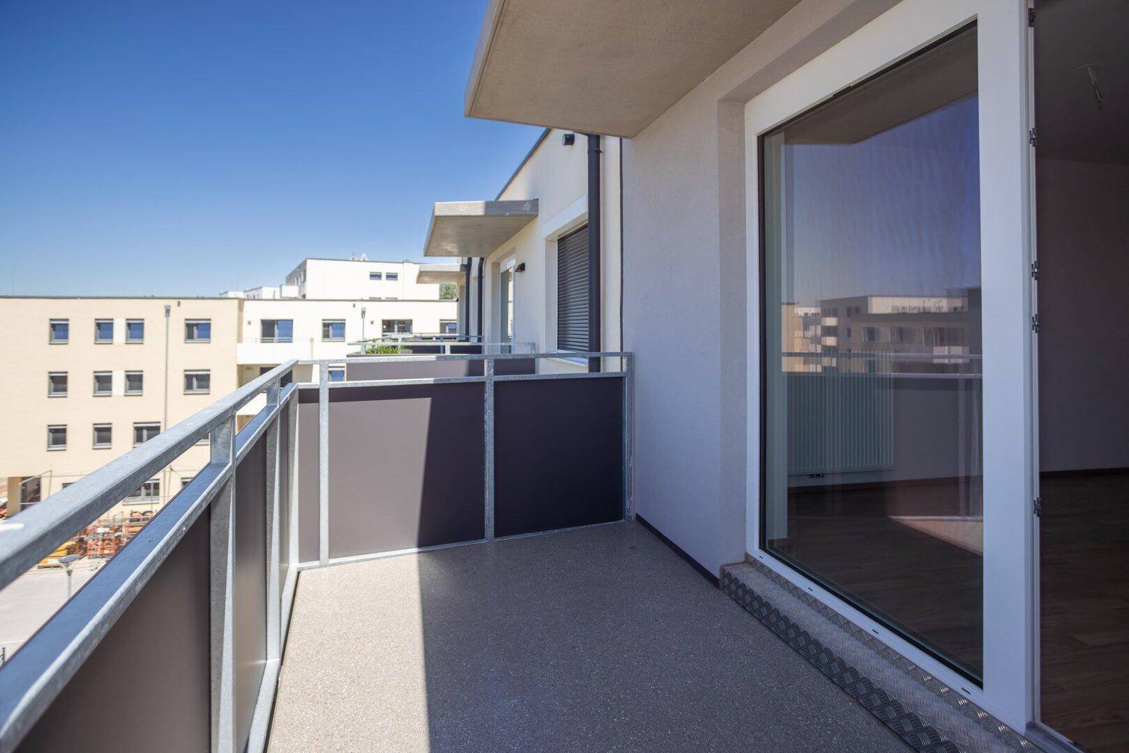 Langer Balkon mit Metallgeländer und Blick entlang der modernen Gebäudefassade.
