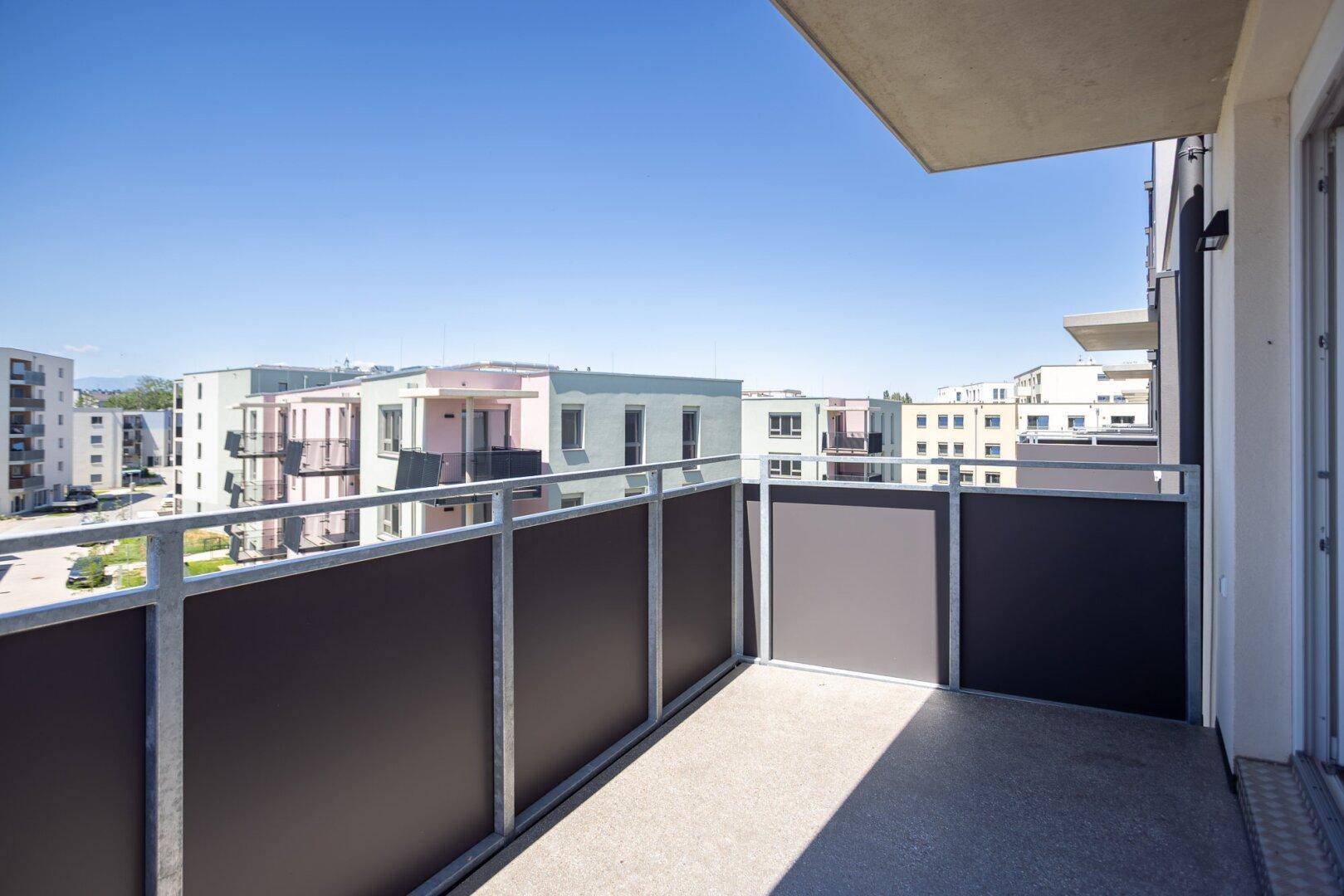 Sonniger Balkon mit Blick auf moderne Wohngebäude und umliegende Bebauung.
