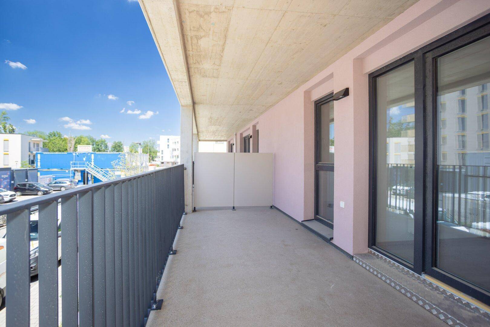 Heller Balkon mit grauen Geländern und Blick auf die städtische Umgebung und andere Gebäude.