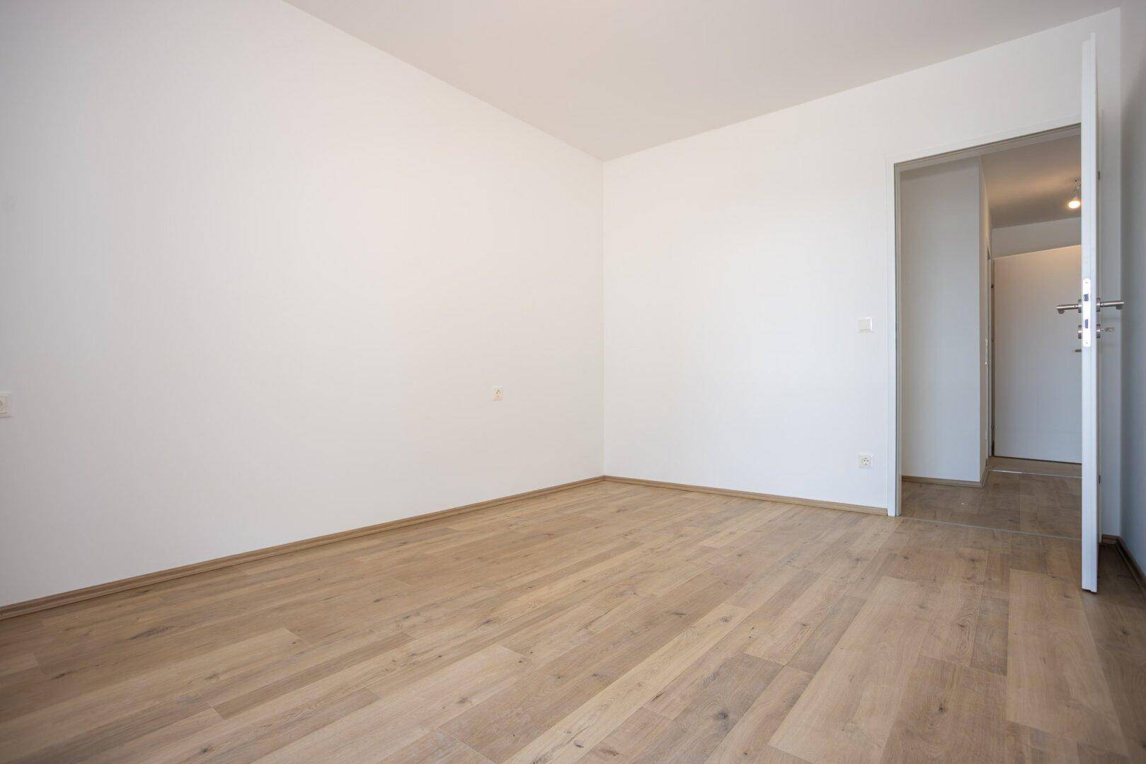 Geräumiges Zimmer mit hellem Laminatboden und weiß gestrichenen Wänden, vielseitig nutzbar.