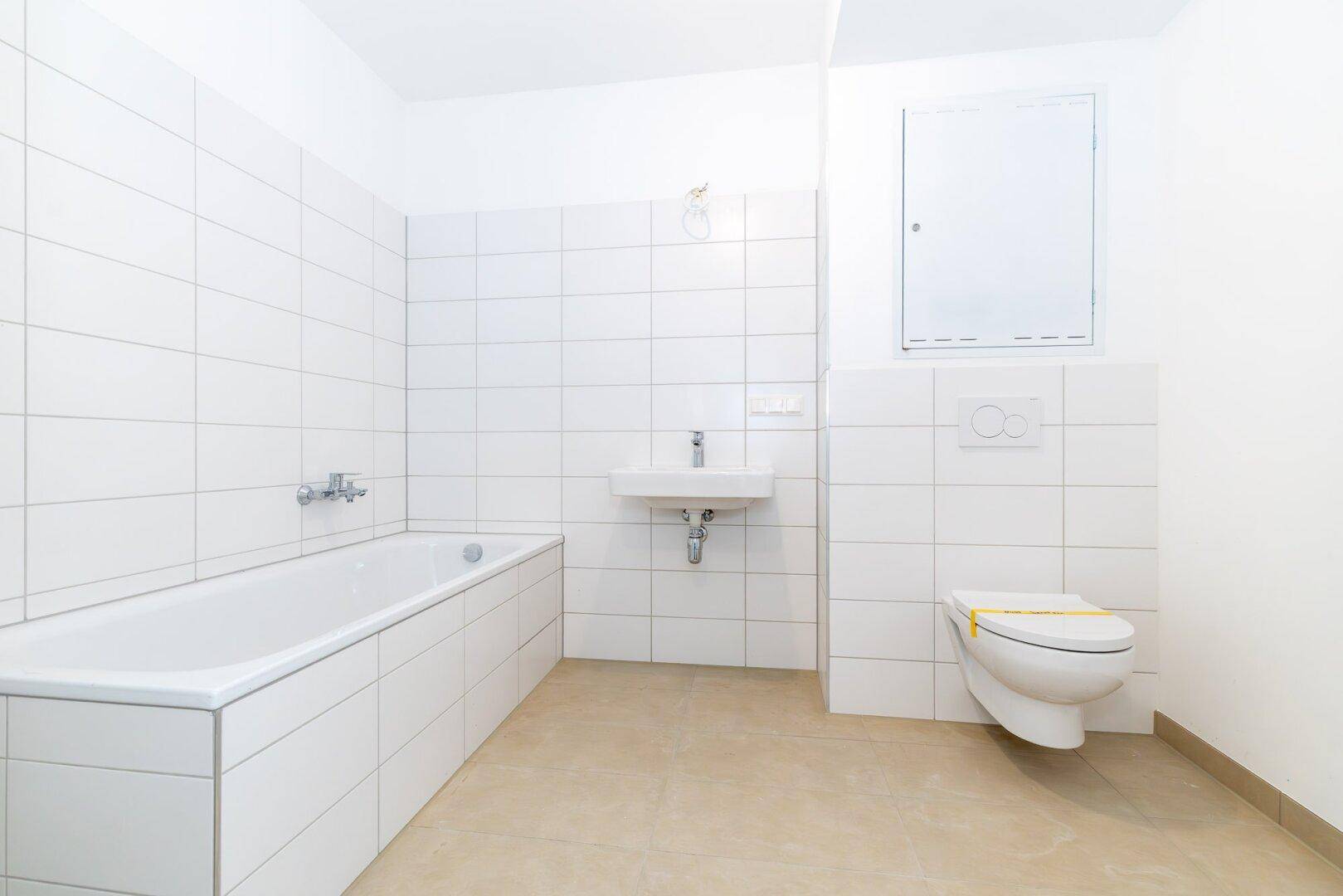 Modernes Badezimmer mit Badewanne, Wand-WC und weiß gefliesten Wänden.