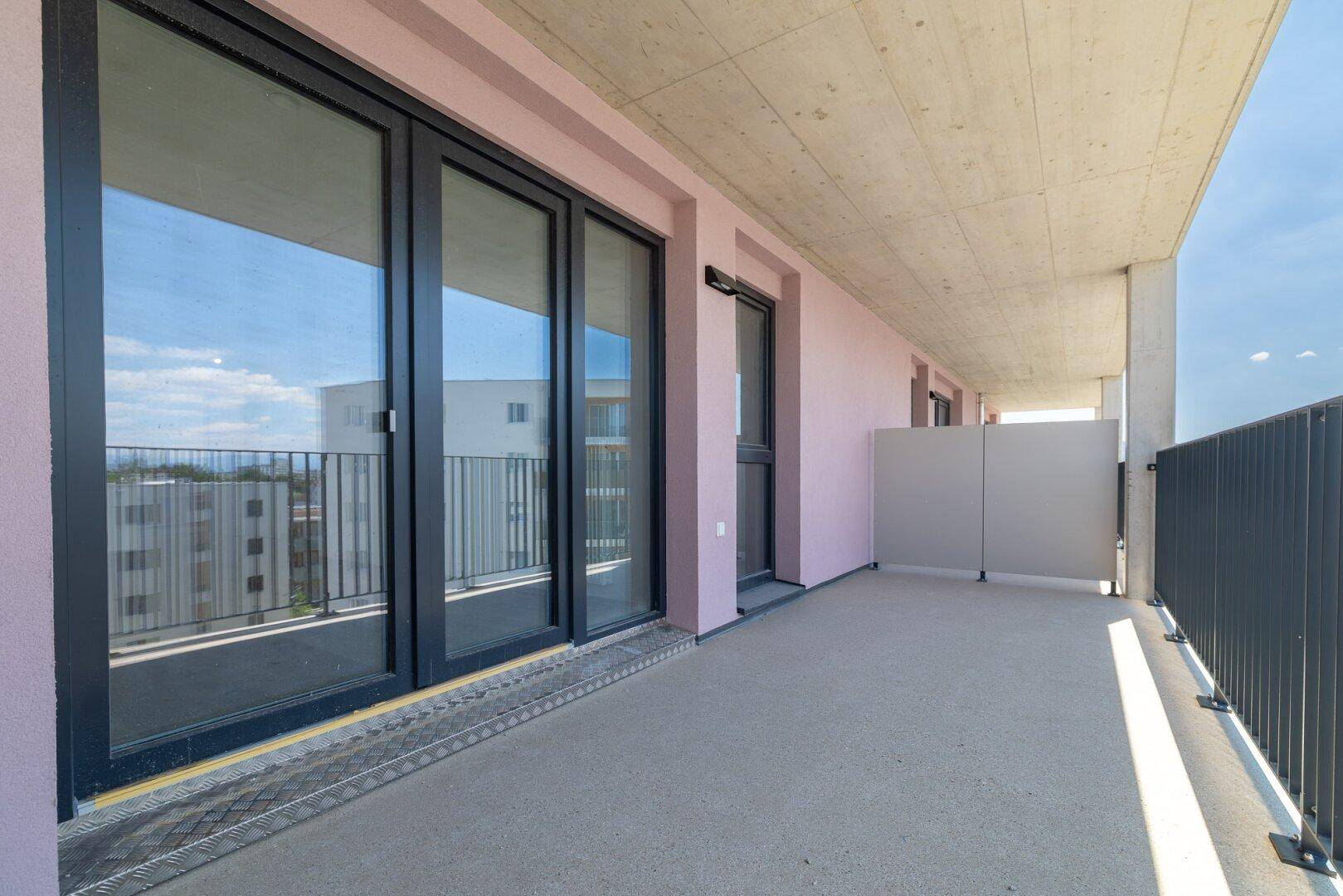 Geräumiger Balkon mit dunklen Fensterrahmen und Sichtschutz, ideal für entspannte Stunden im Freien.