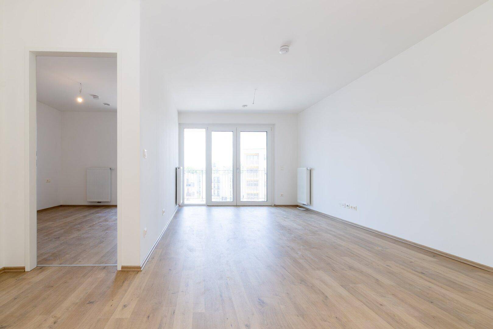 Geräumiges, helles Zimmer mit Laminatboden und Balkonzugang, bietet vielseitige Gestaltungsmöglichkeiten.