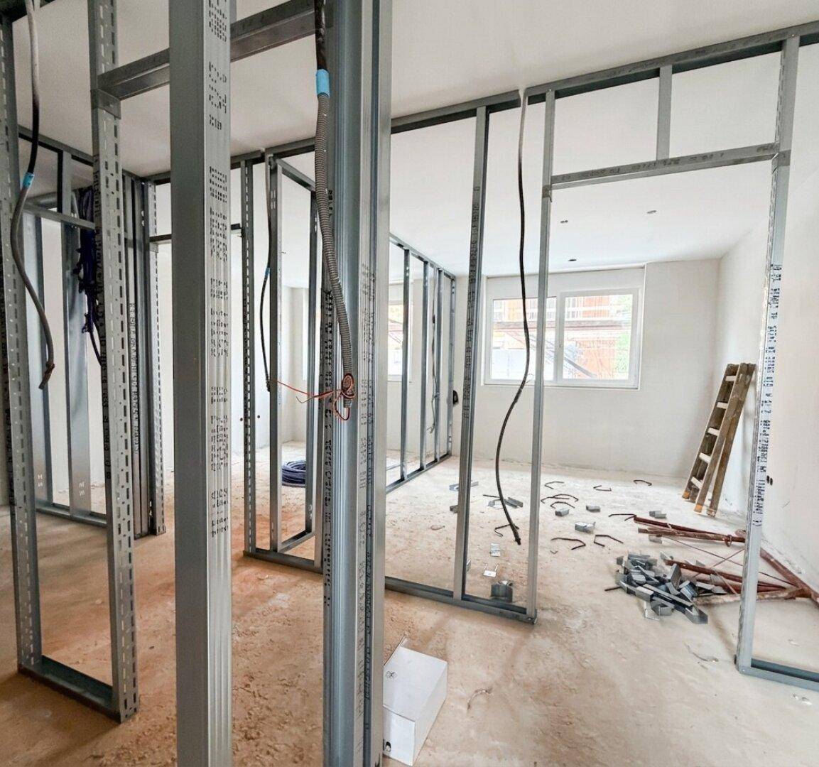 Rohbau-Innenraum mit Metallständerwerk für Trockenbauwände und sichtbaren Elektroinstallationen.