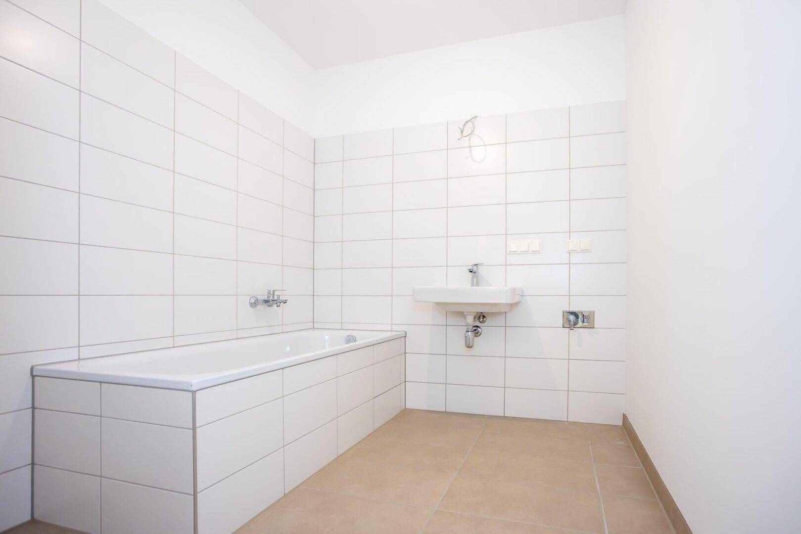 Modernes Badezimmer mit weiß gefliesten Wänden, Badewanne und einem einzelnen Waschbecken.