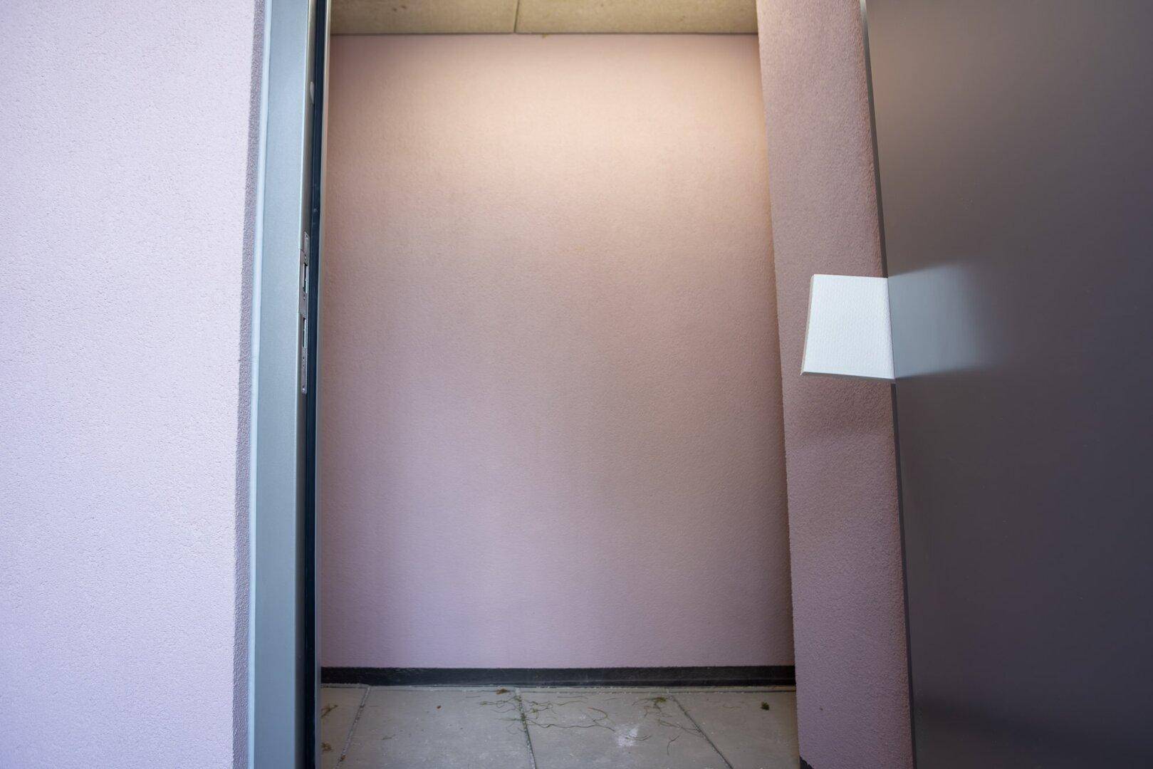 Unfertiger Abstellraum mit rosa gestrichenen Wänden und einem einfachen Betonboden.