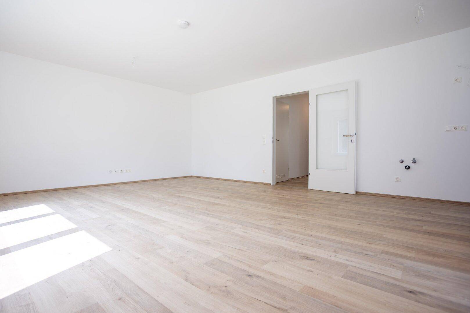 Geräumiges Zimmer mit hellem Laminatboden und weißen Wänden, ideal für individuelle Einrichtungsideen.
