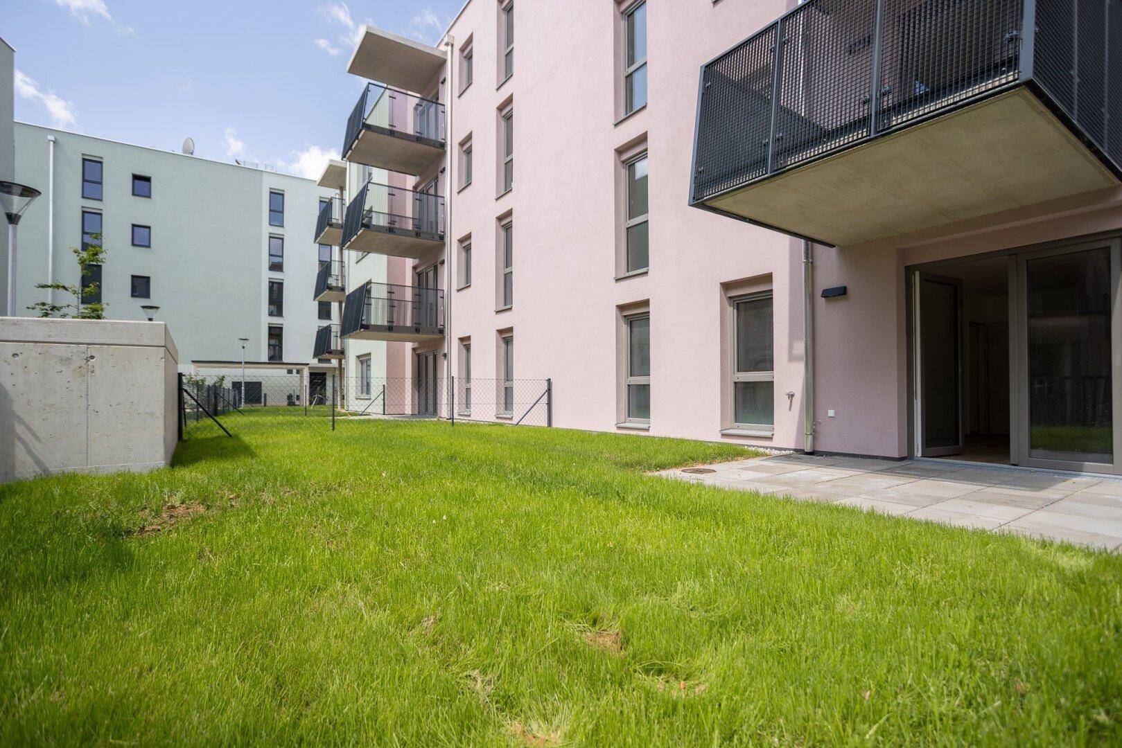 Moderne Wohnanlage mit Balkonen und gepflegter Rasenfläche im Außenbereich.