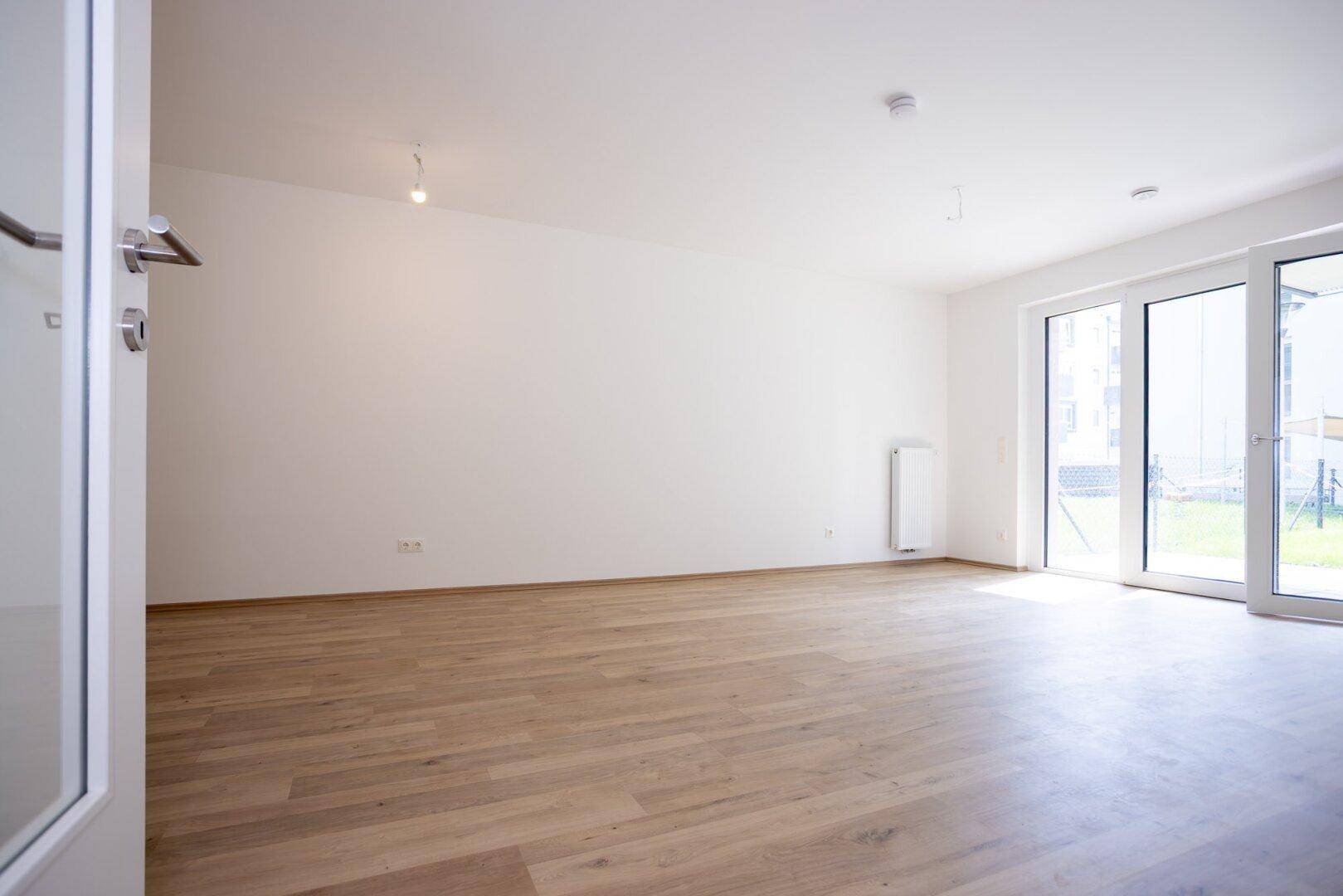 Geräumiges, helles Wohnzimmer mit Laminatboden und direktem Zugang zum Außenbereich.