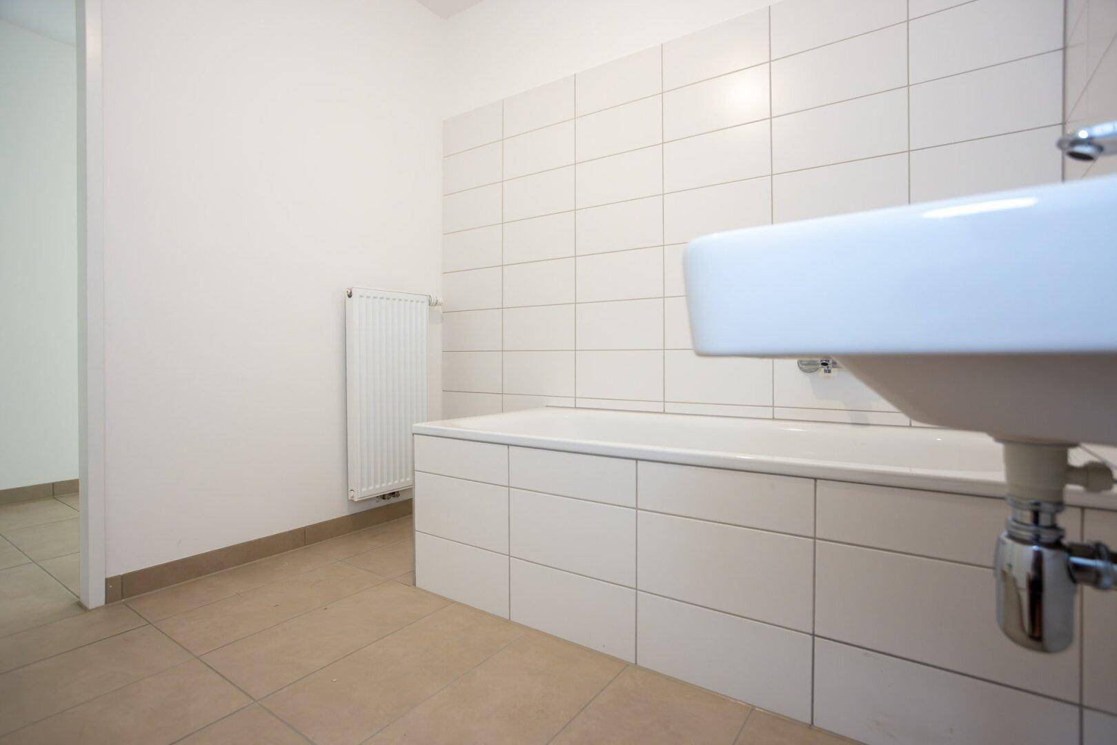 Modernes Badezimmer mit Badewanne, Waschbecken und weißen Wandfliesen.