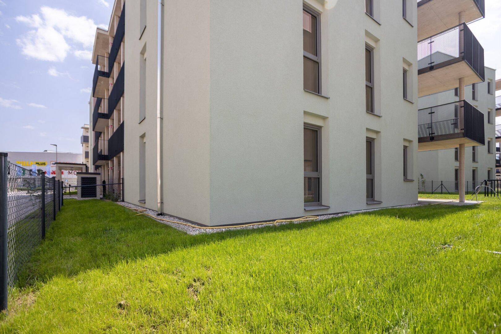 Seitenansicht eines modernen Neubaus mit gepflegtem Rasen und schlichten Fenstern.