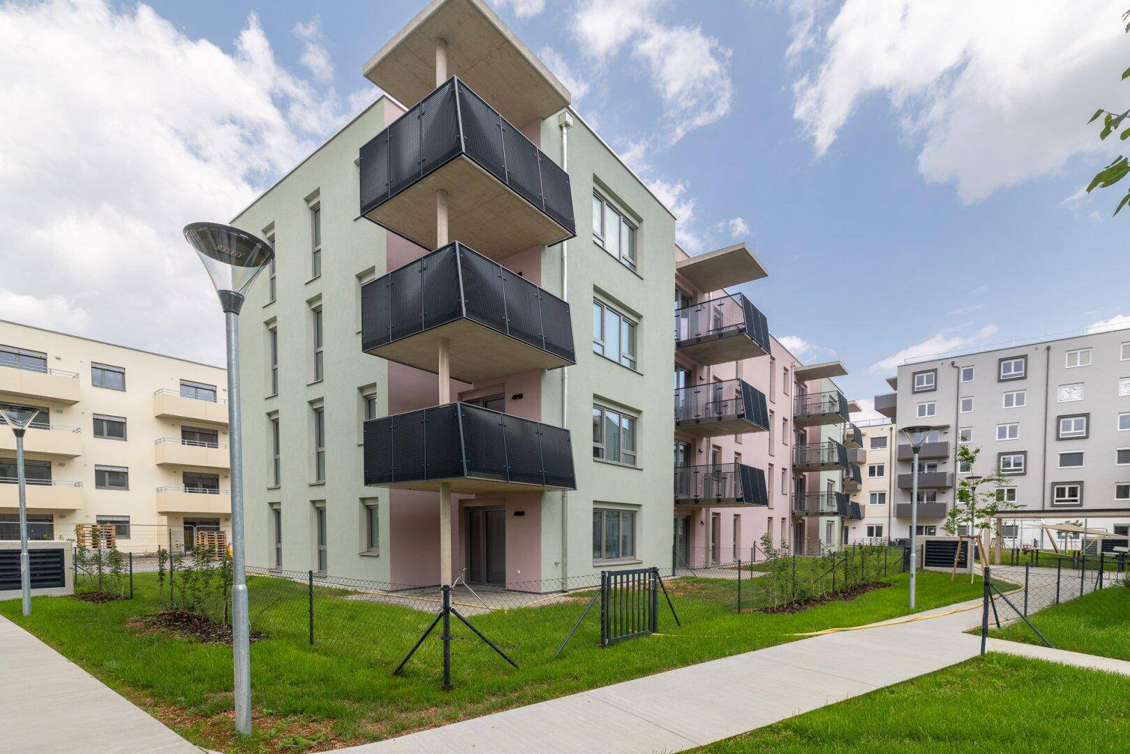 Zeitgenössische Wohngebäude mit Balkonen und gepflegten Grünflächen unter blauem Himmel.