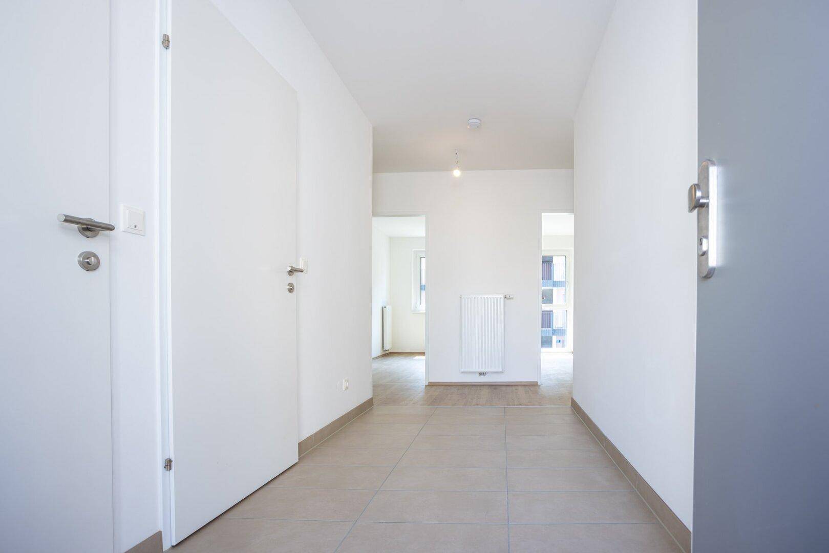 Heller Flur mit Fliesenboden und Zugang zu verschiedenen Zimmern der Wohnung.