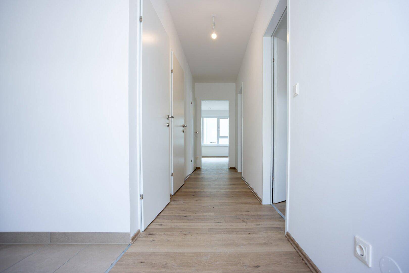 Heller Flur mit Laminatboden und mehreren Türen, der zu den verschiedenen Räumen führt.