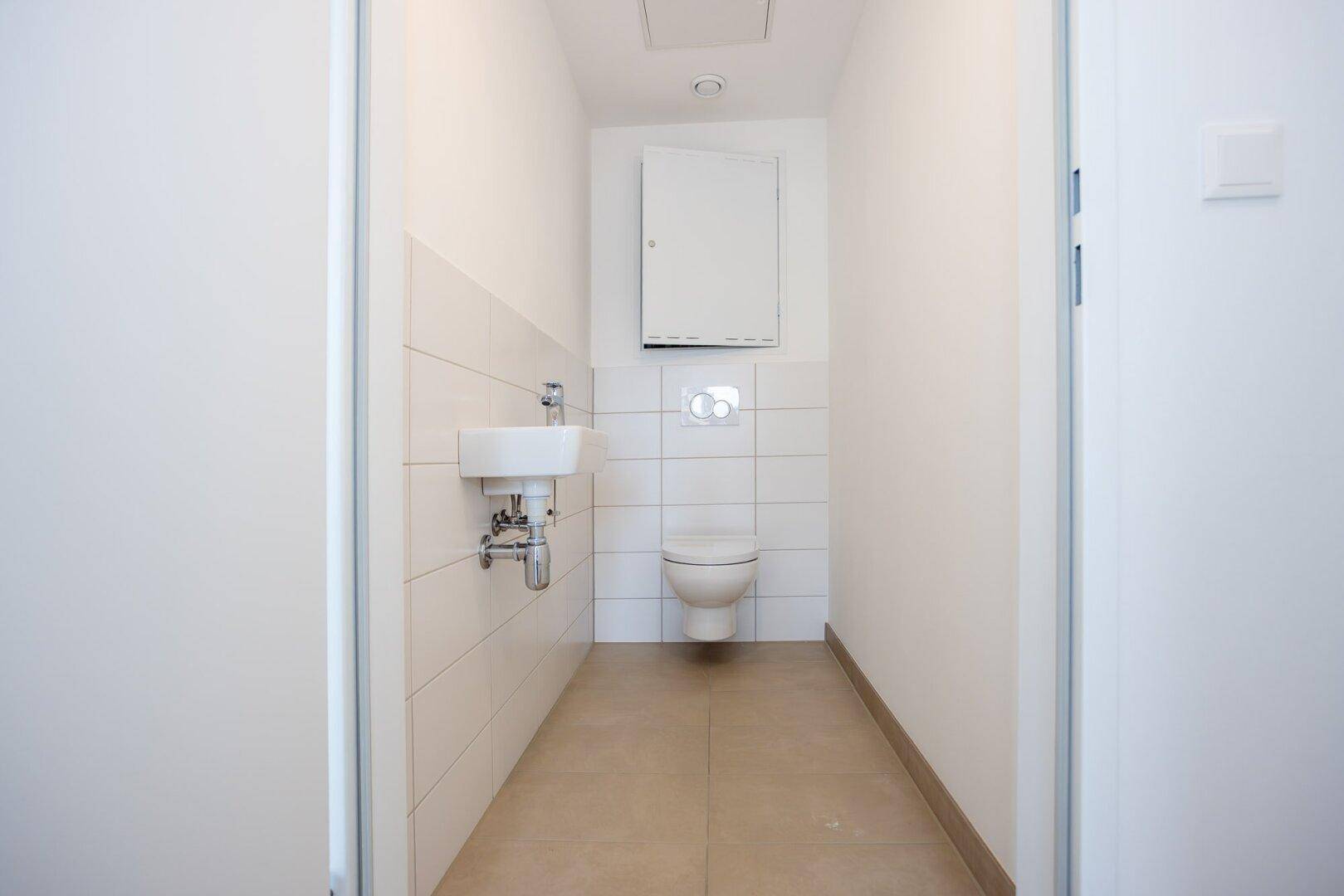 Kleines Gäste-WC mit wandhängender Toilette und Handwaschbecken.