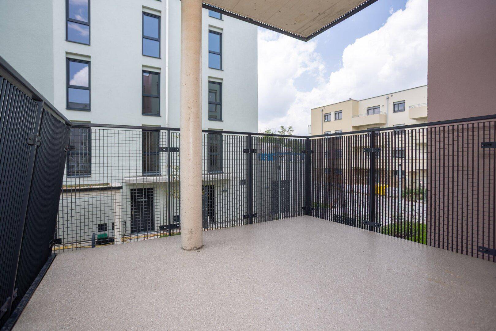 Balkon mit Gittergeländer und Blick auf die umliegenden Gebäude der Wohnanlage.
