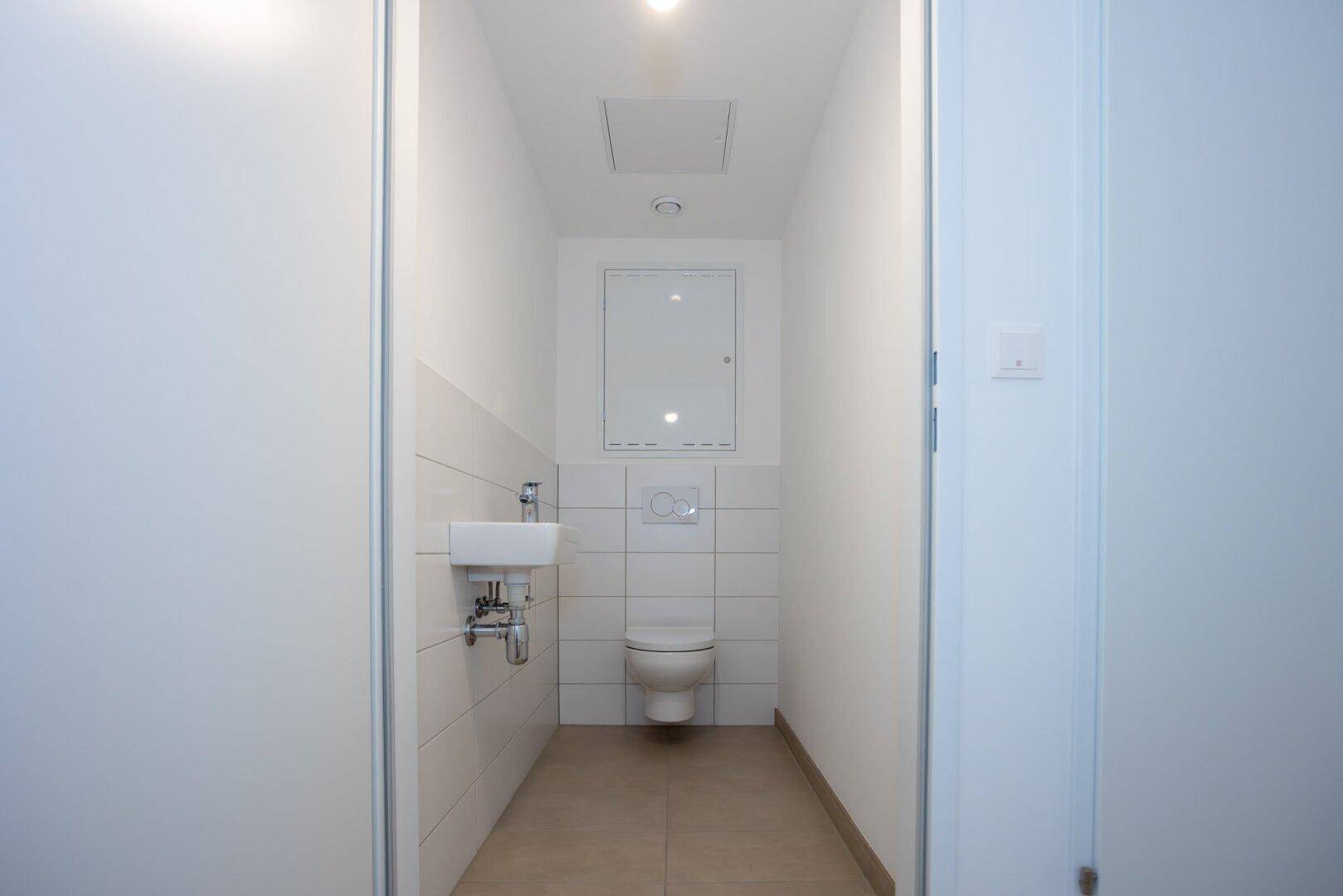 Kleines Gäste-WC mit wandhängender Toilette und Waschbecken.
