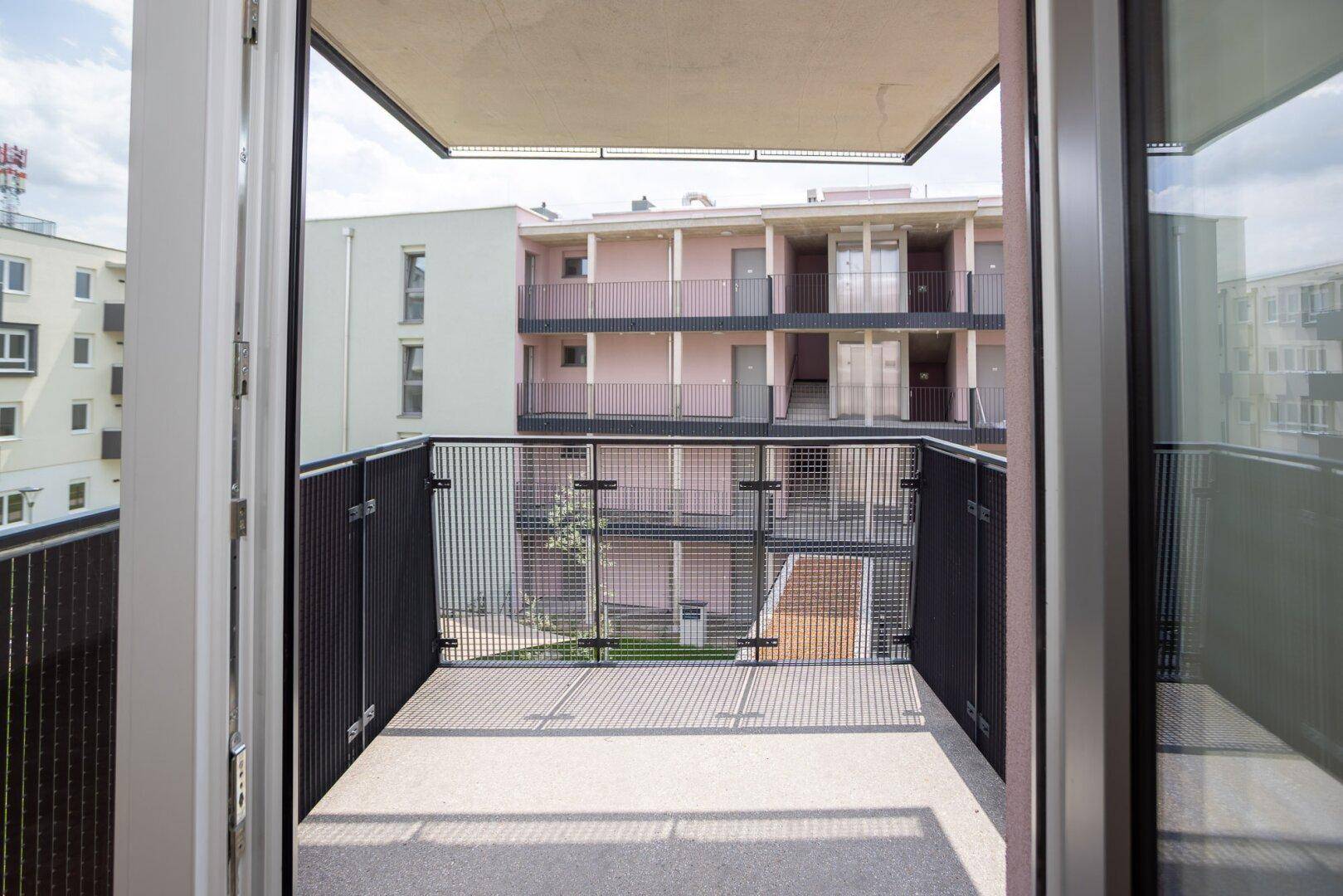 Blick vom Balkon auf den Innenhof und die umliegenden modernen Wohngebäude.