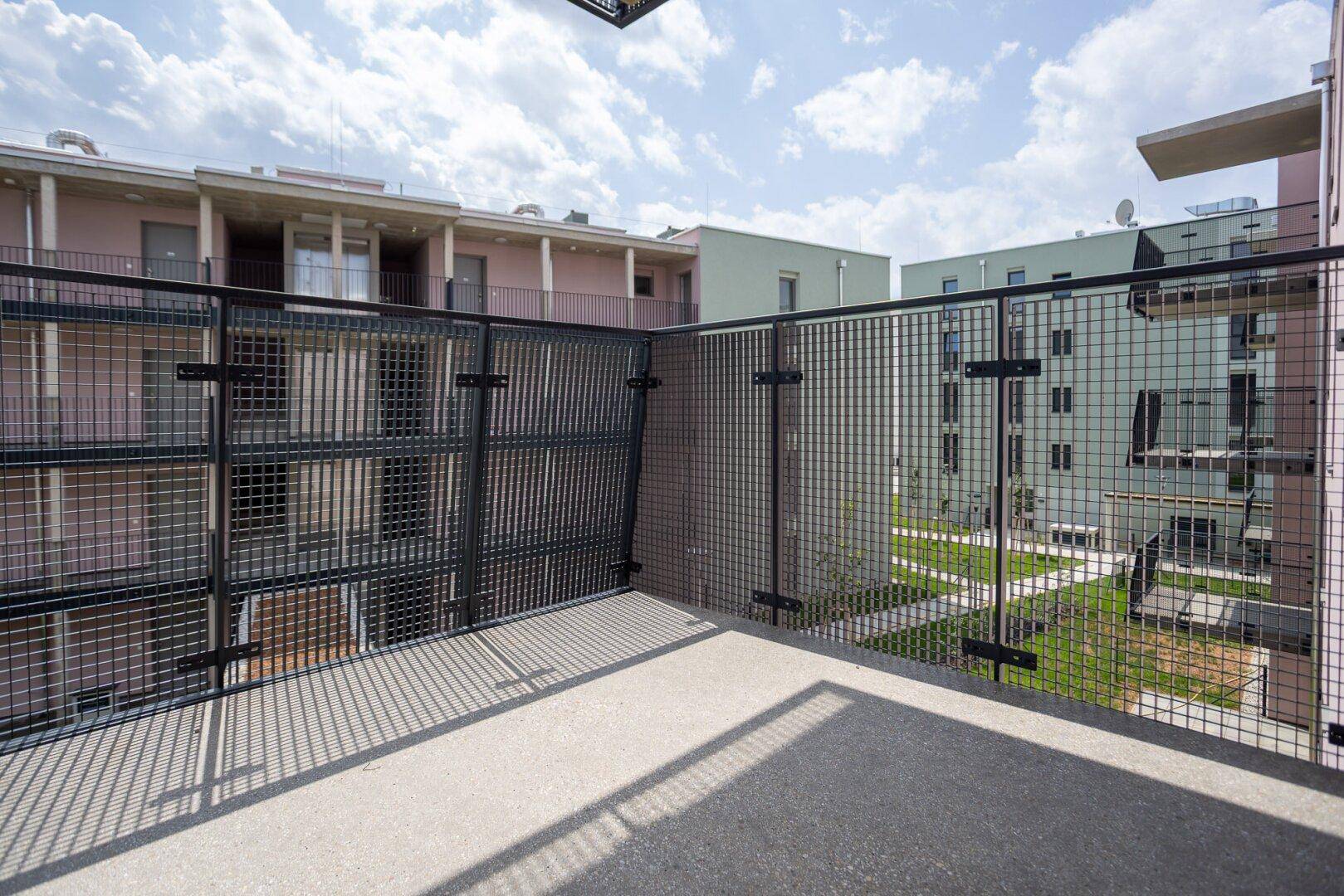 Geräumiger Balkon mit Metallgeländer und Blick auf die umliegenden Wohngebäude und den Innenhof.