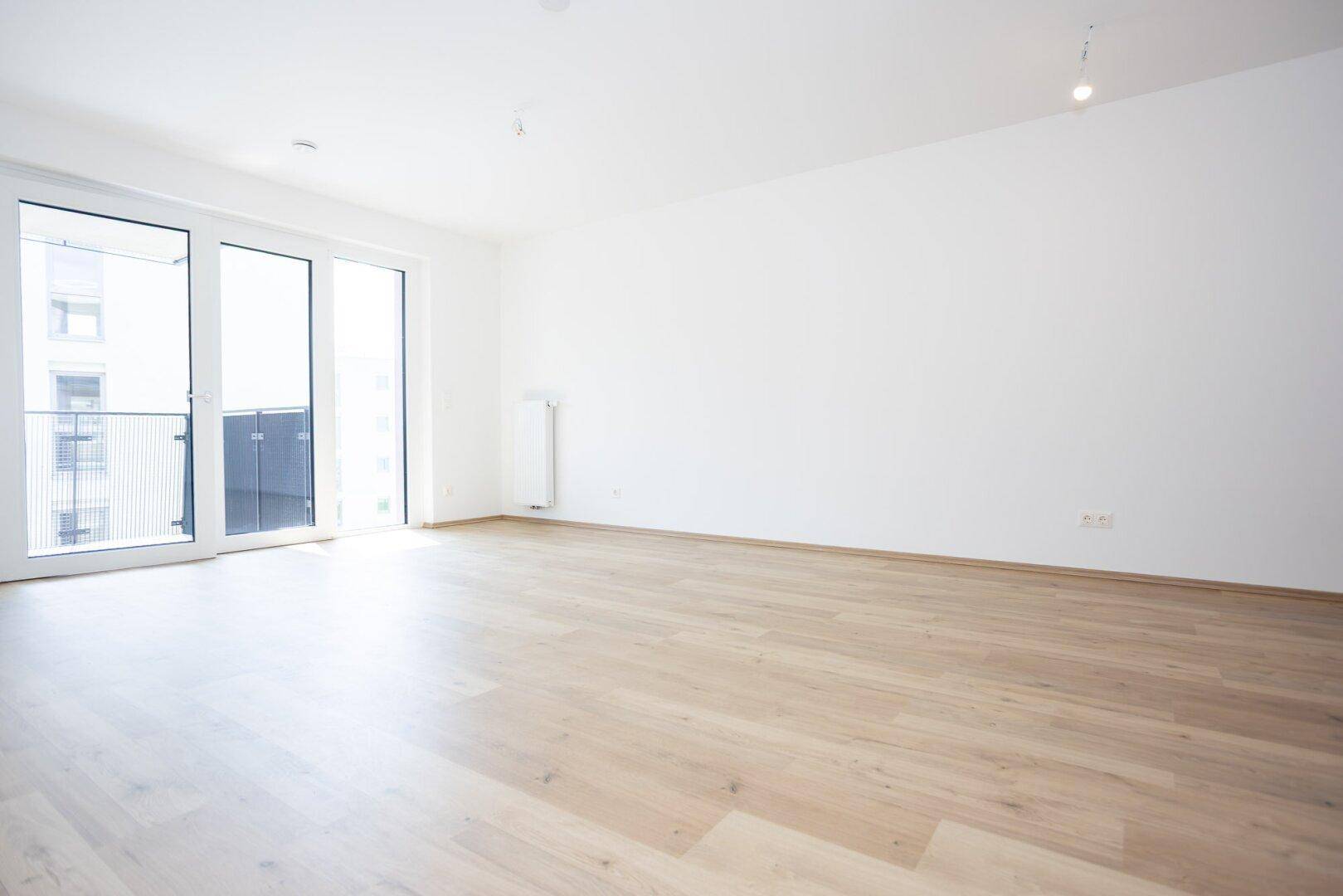 Geräumiges, helles Wohnzimmer mit Holzboden und direktem Zugang zum Außenbereich.