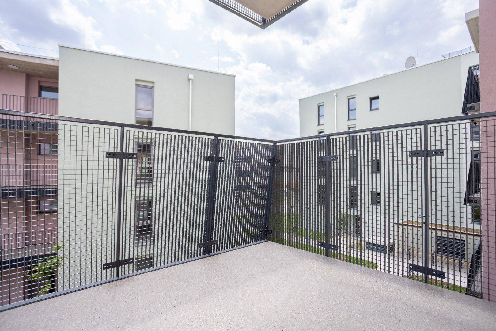 Geräumiger Balkon mit modernem Metallgeländer und Blick auf die umliegenden Gebäude.