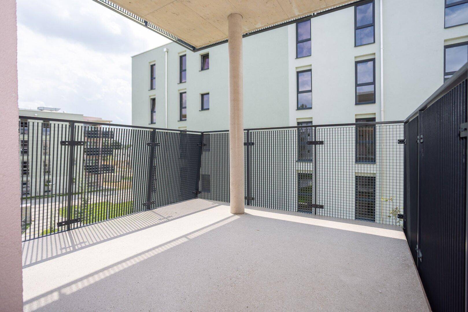 Geräumiger Balkon mit modernem Metallgeländer und Blick auf die umliegenden Gebäude.