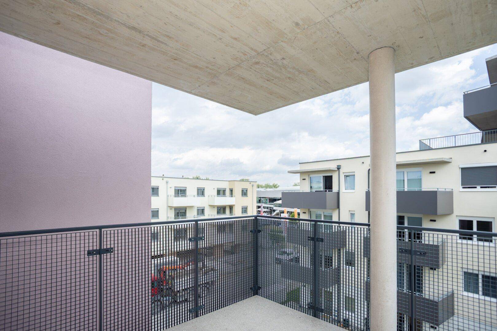Balkon mit Blick auf die umliegenden modernen Wohngebäude und den Himmel.