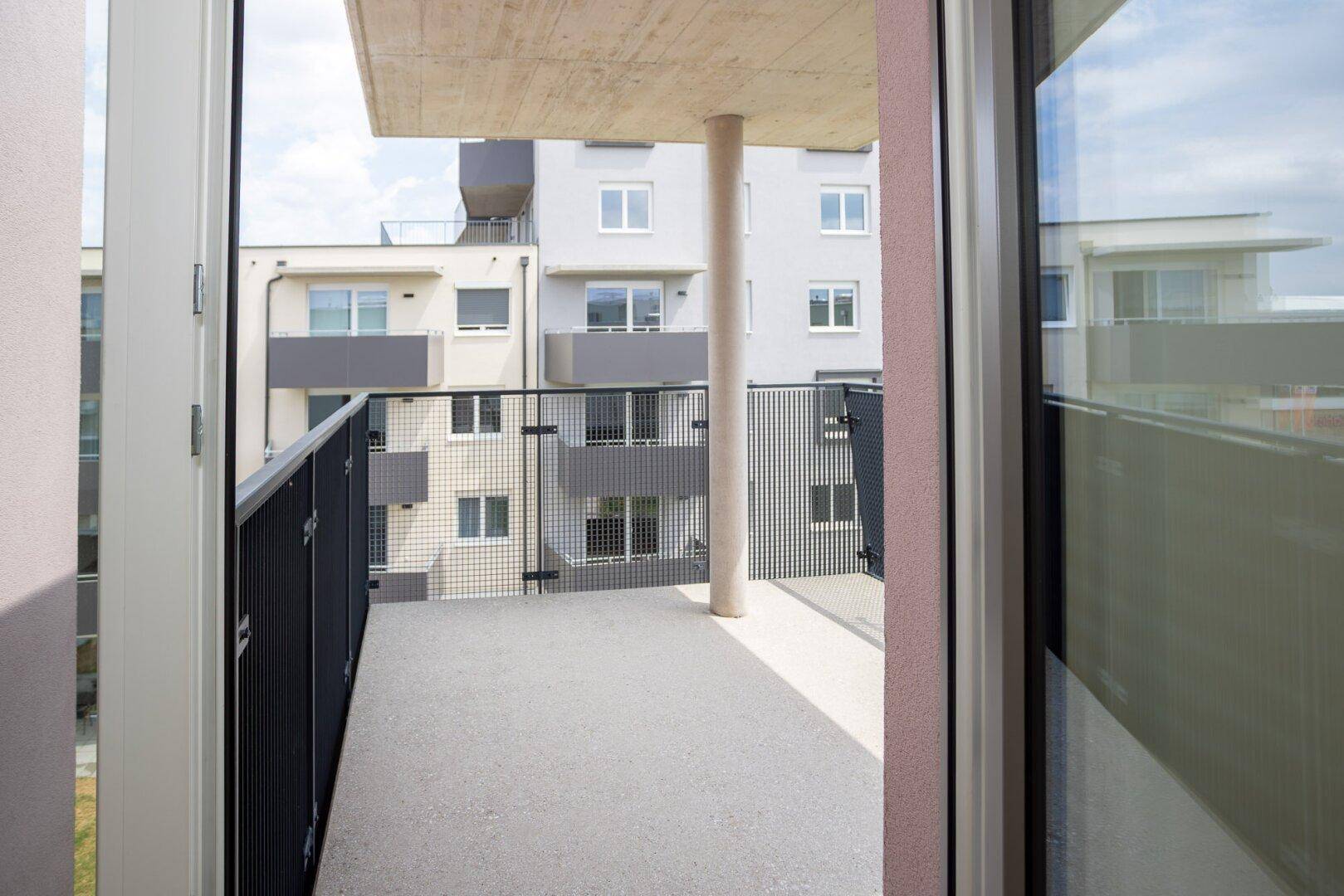 Balkon mit Blick auf die moderne Wohnbebauung und den Himmel, ideal zum Entspannen.