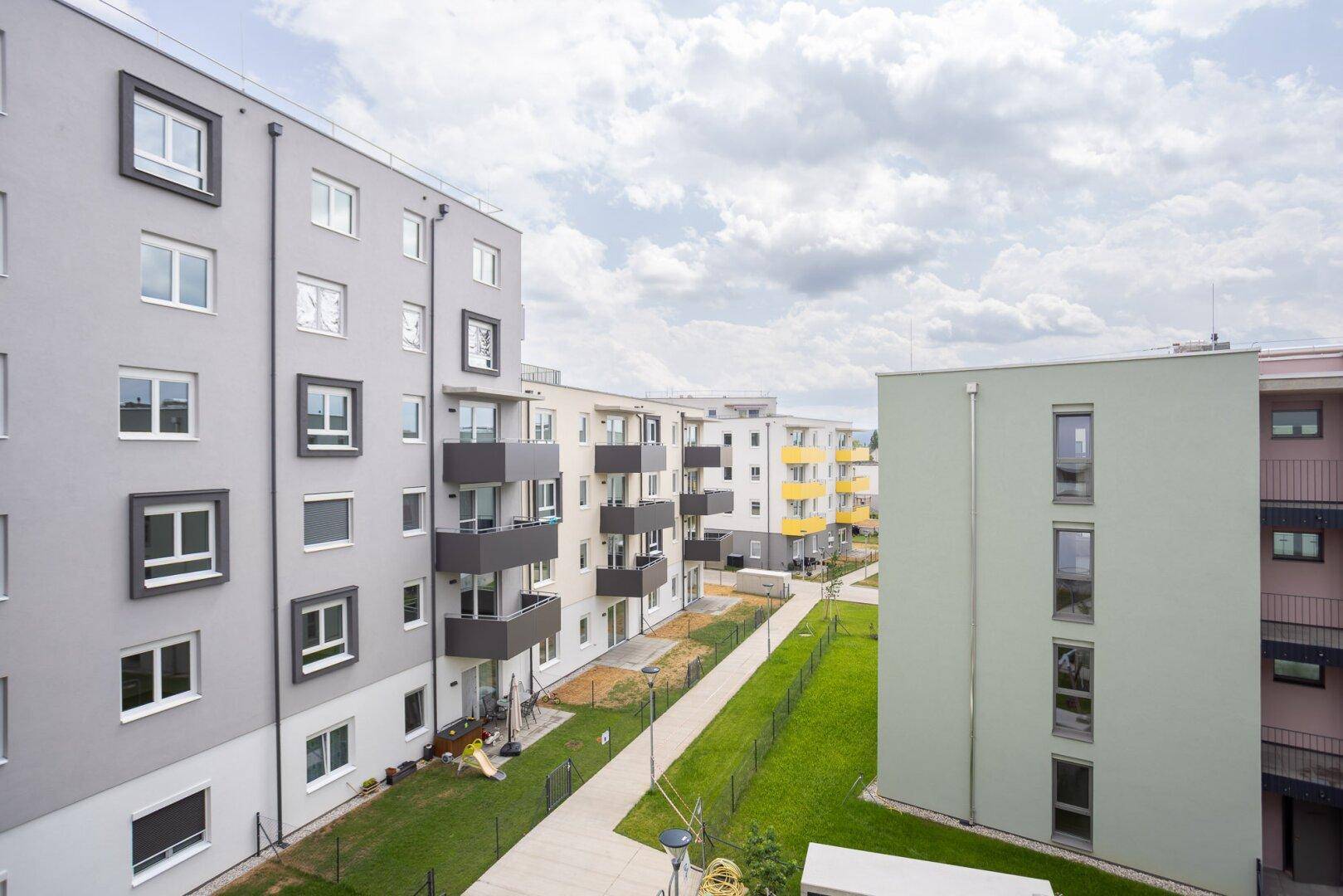 Moderne Wohnanlage mit mehreren Gebäuden, gepflegten Grünflächen und Gehwegen.