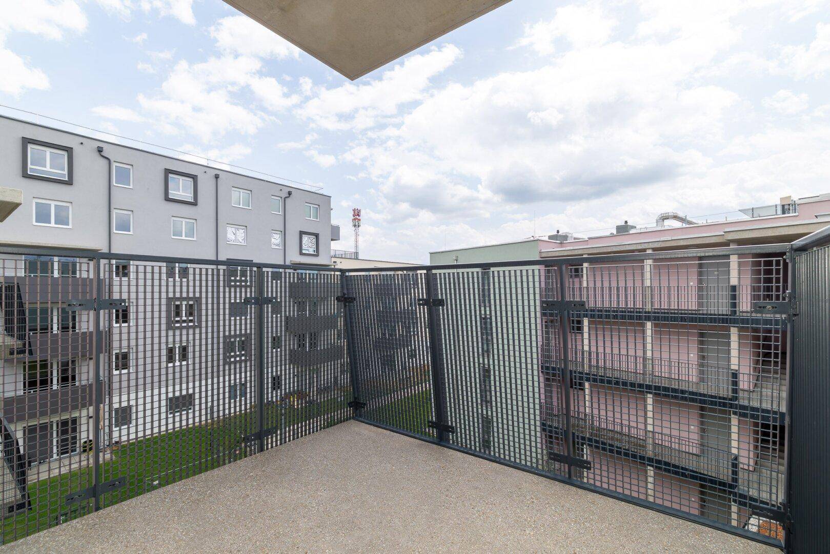 Blick von einem Balkon auf die umliegenden modernen Wohngebäude und den grünen Innenhof.