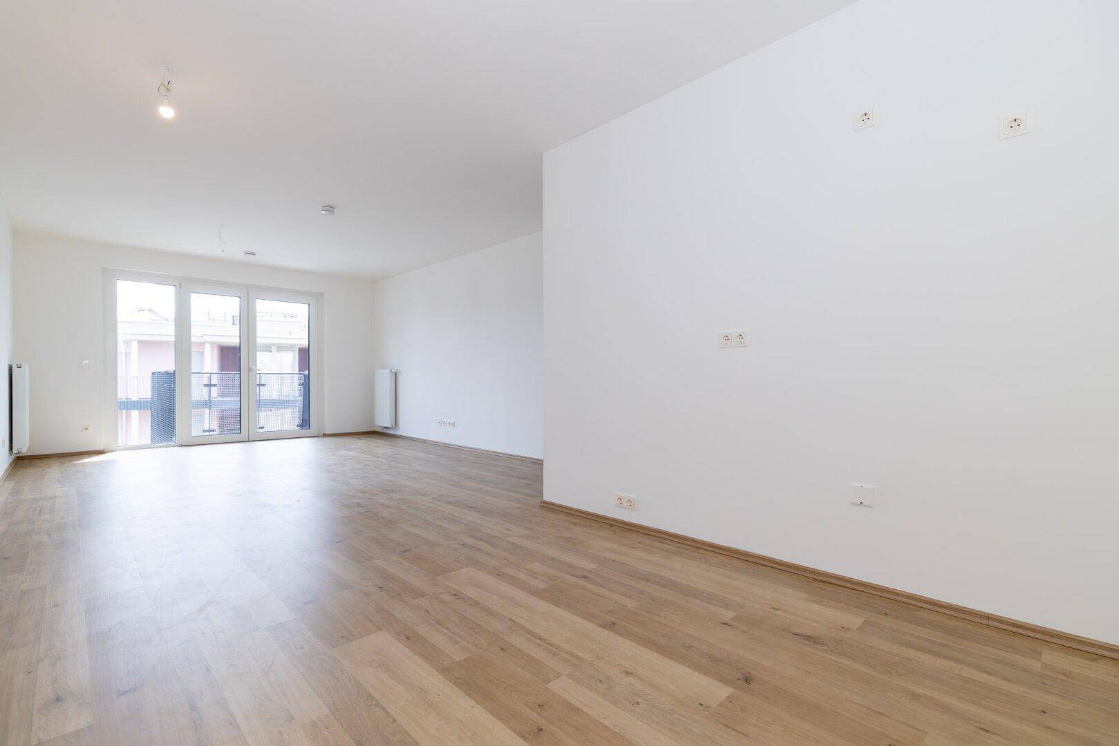 Geräumiges, helles Zimmer mit Laminatboden und großen Fenstern, bereit zur individuellen Gestaltung.