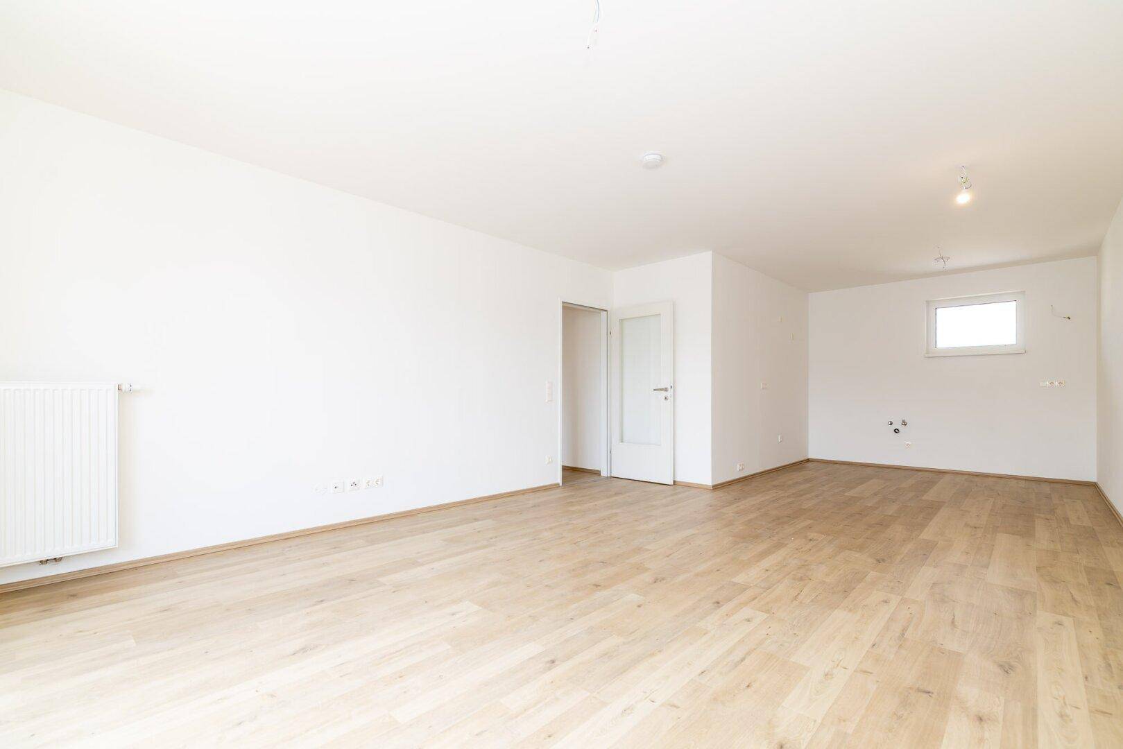 Helles Schlafzimmer mit Laminatboden und einem Fenster, ideal für Ruhe und Entspannung.
