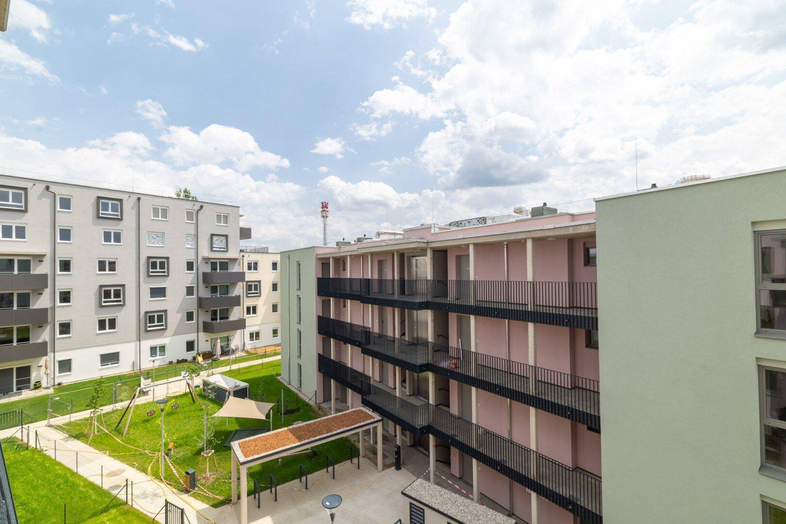 Übersicht der modernen Wohnanlage mit begrüntem Innenhof und Kinderspielplatz.