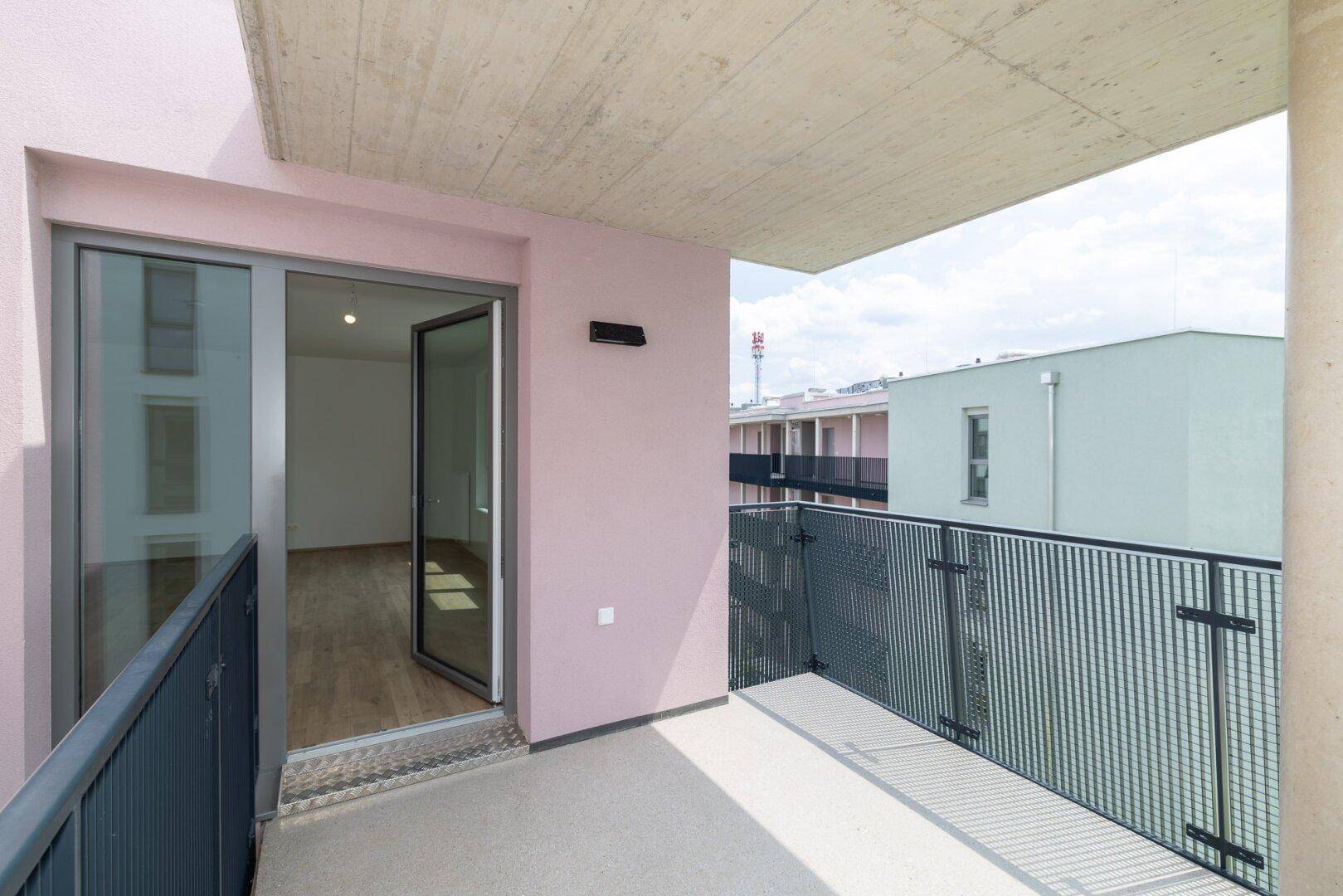 Moderner Balkon mit Metallgeländer und Blick auf die umliegenden Gebäude der Wohnanlage.